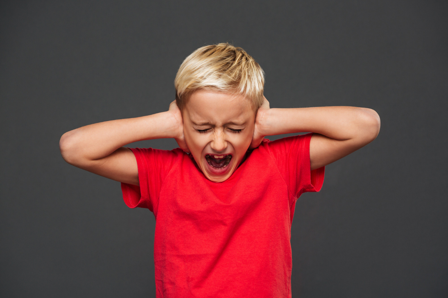 Un niño gritando mientras se tapa los oídos | Fuente: Freepik