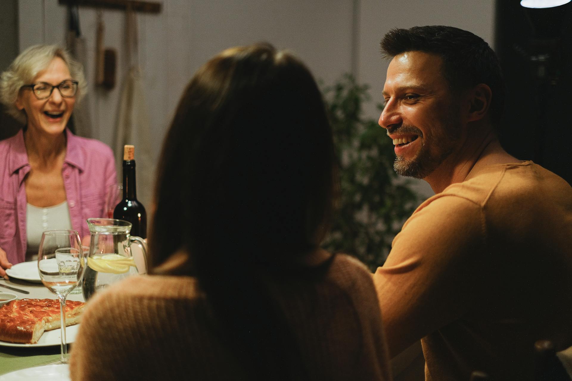 Un hombre riendo en una cena familiar | Fuente: Pexels