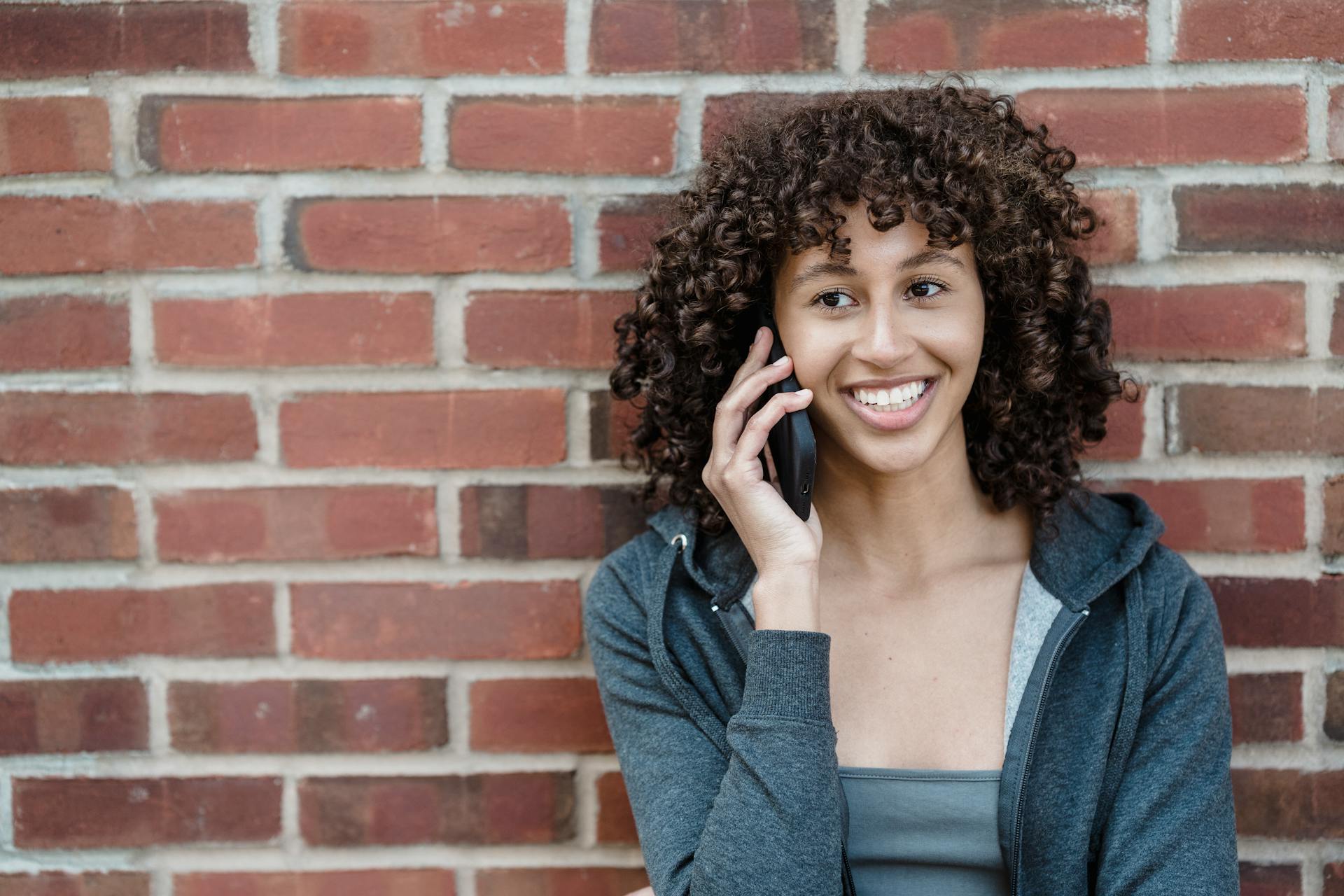 Una mujer responde al teléfono con una sonrisa | Fuente: Pexels