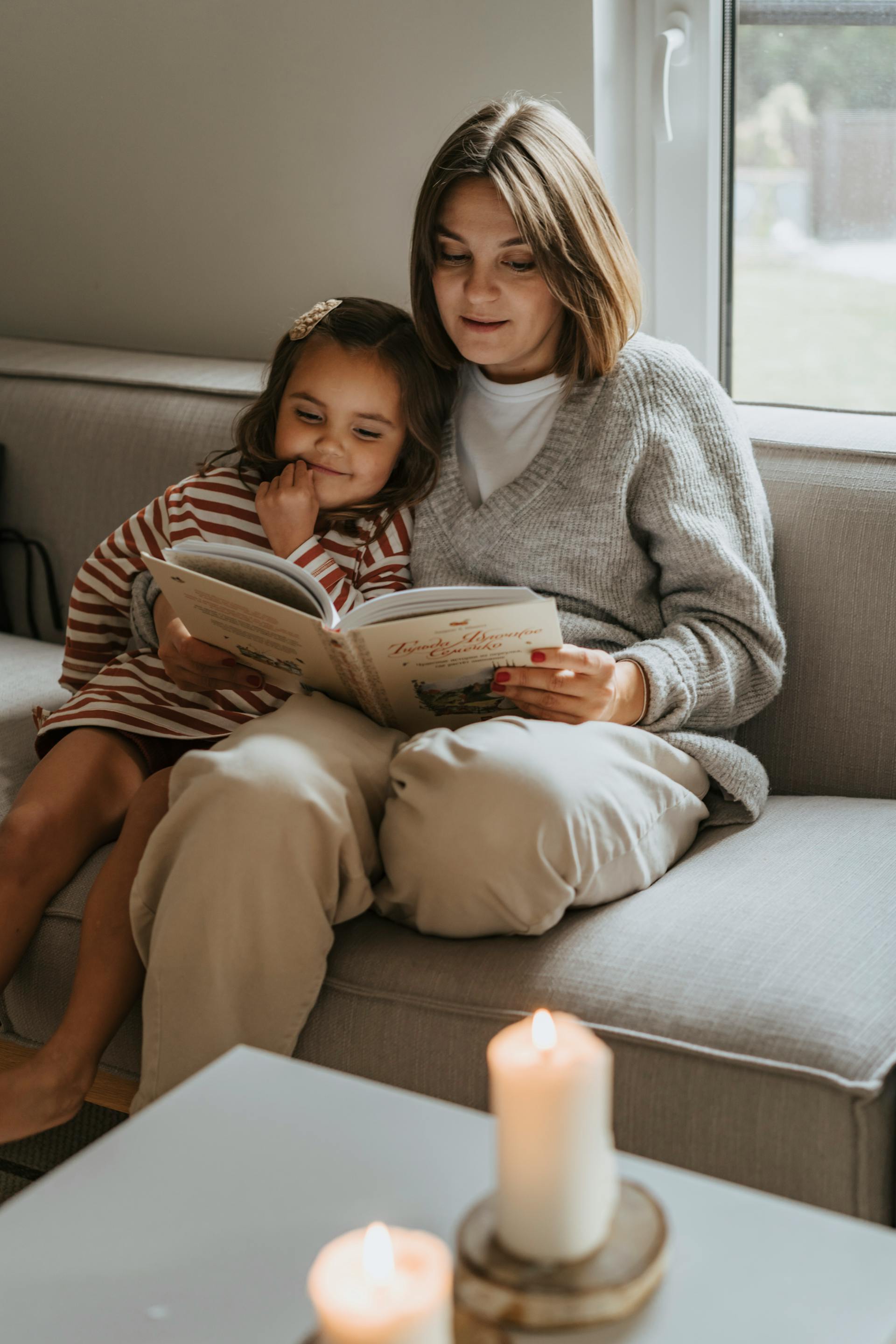 Una mujer leyendo a una niña en un sofá | Fuente: Pexels