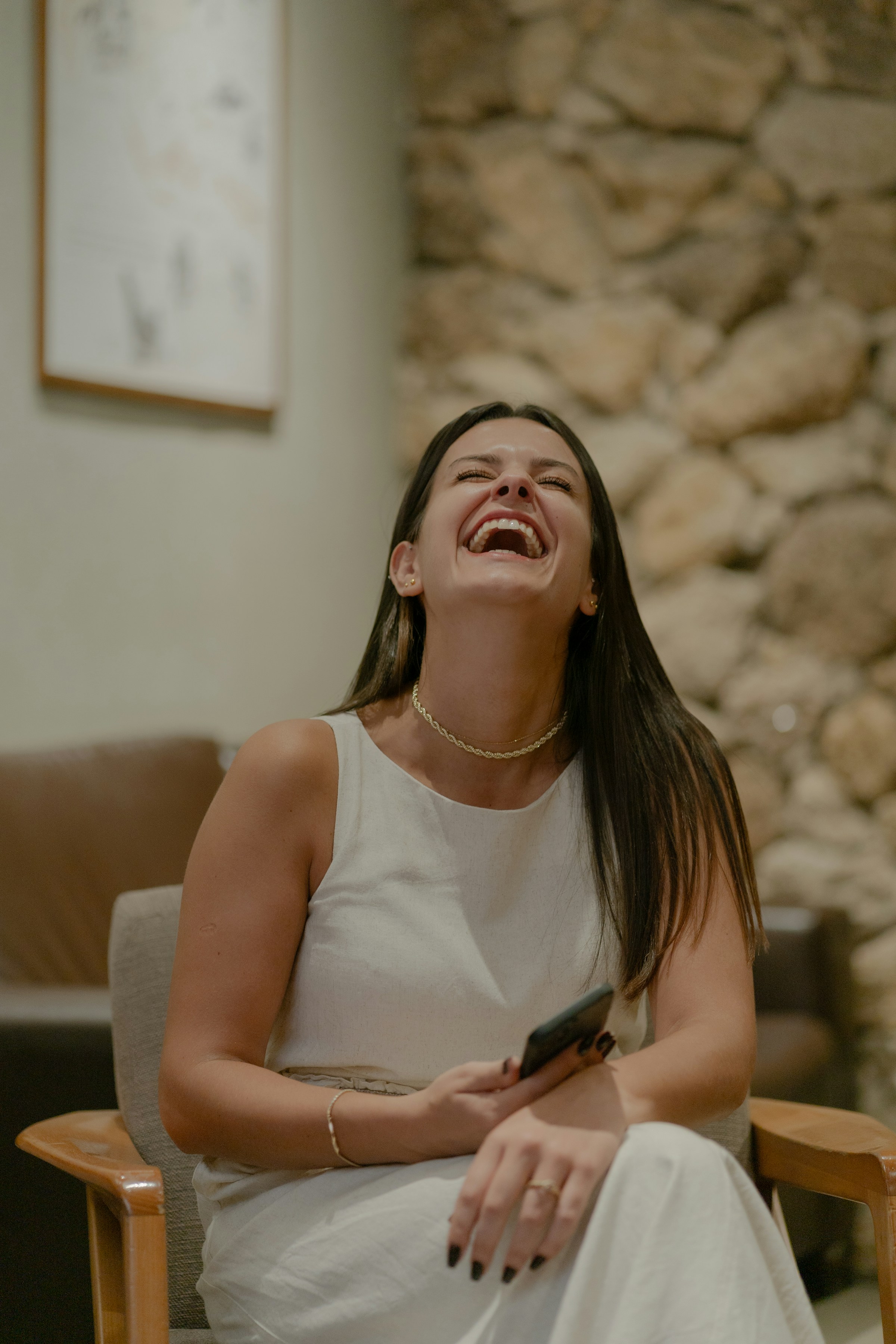 Una mujer riendo mientras sujeta su teléfono | Fuente: Unsplash