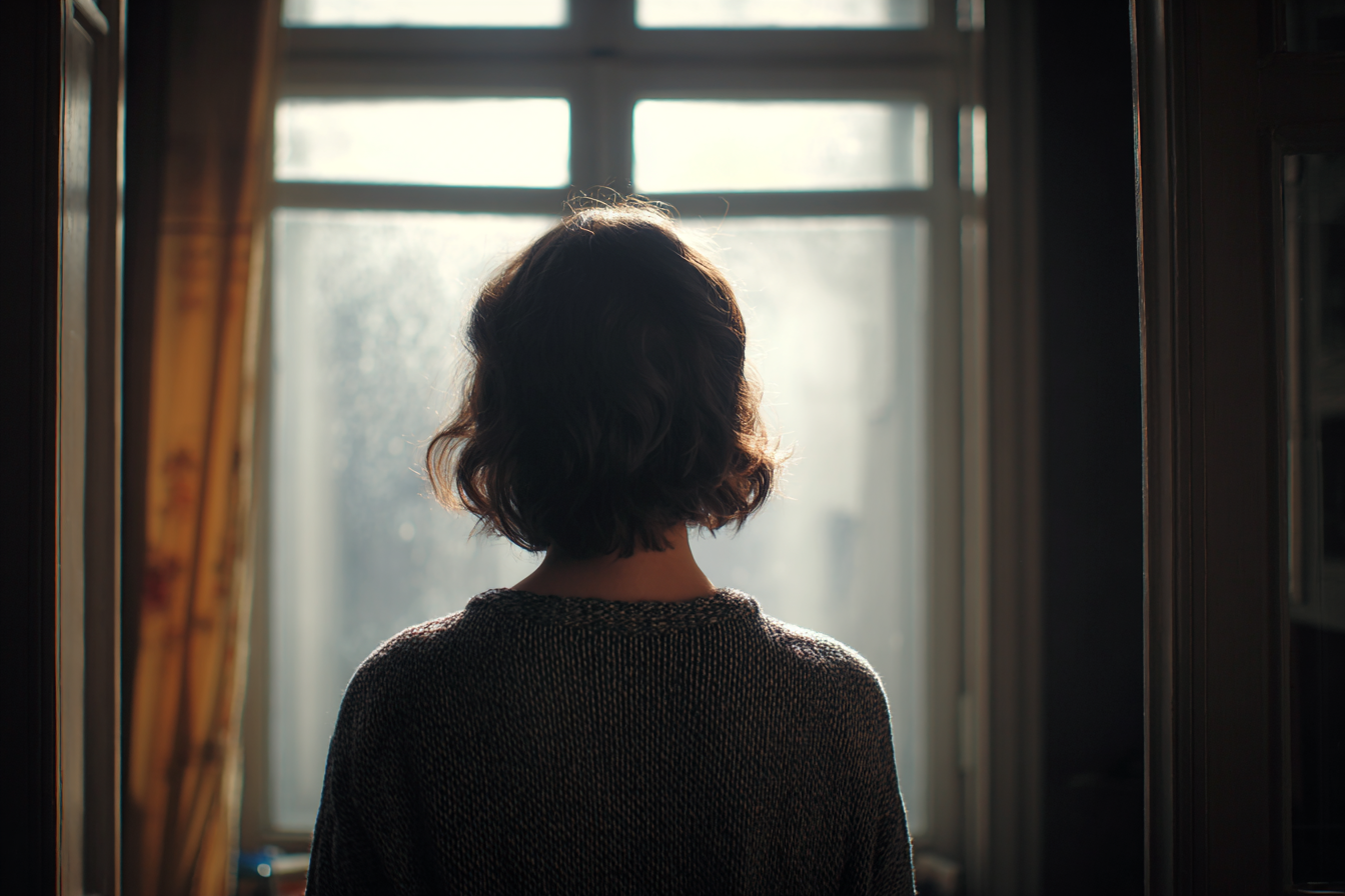 Una mujer junto a una ventana | Fuente: Midjourney
