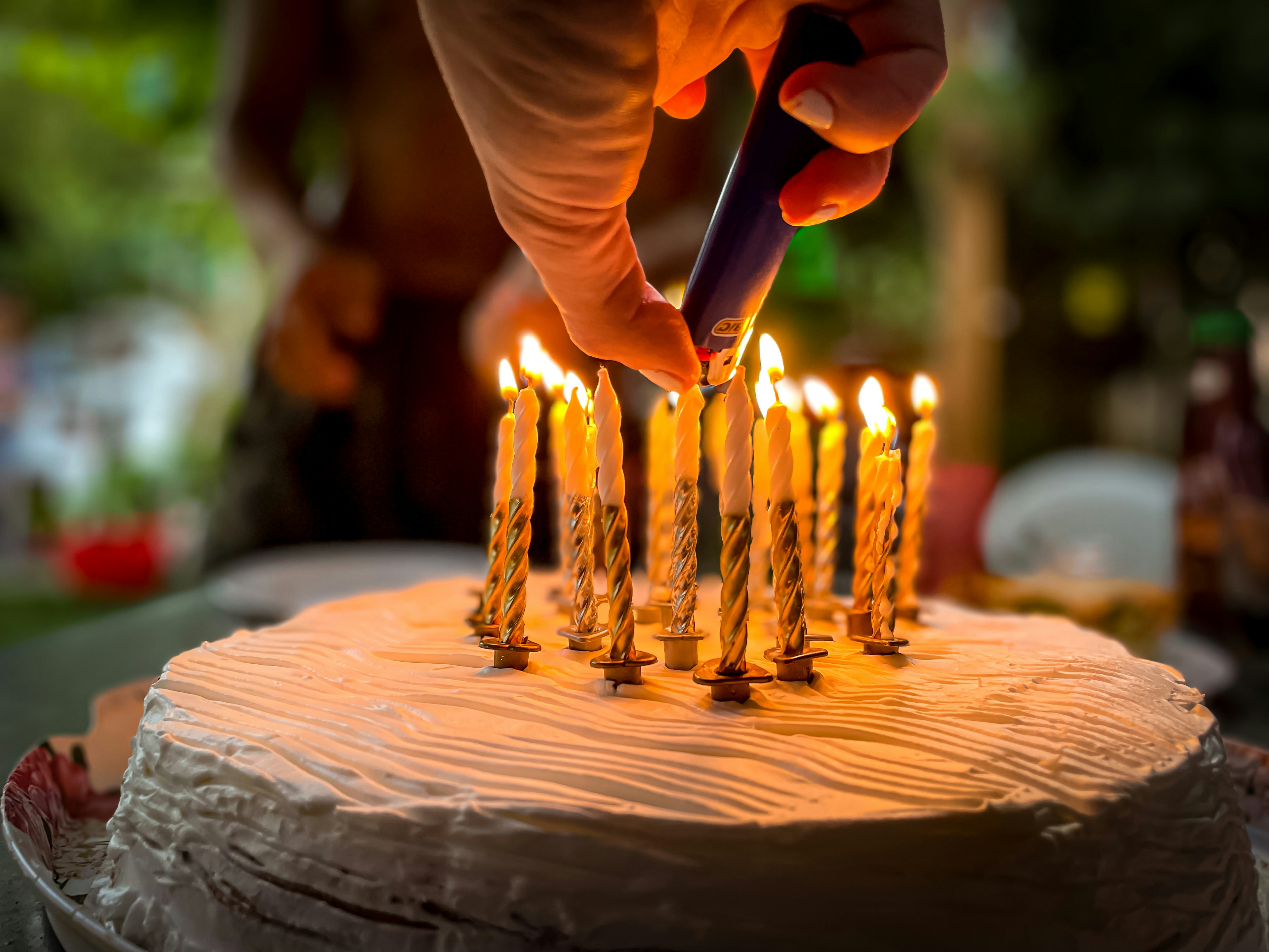 La mano de una mujer encendiendo las velas de un pastel | Fuente: Unsplash