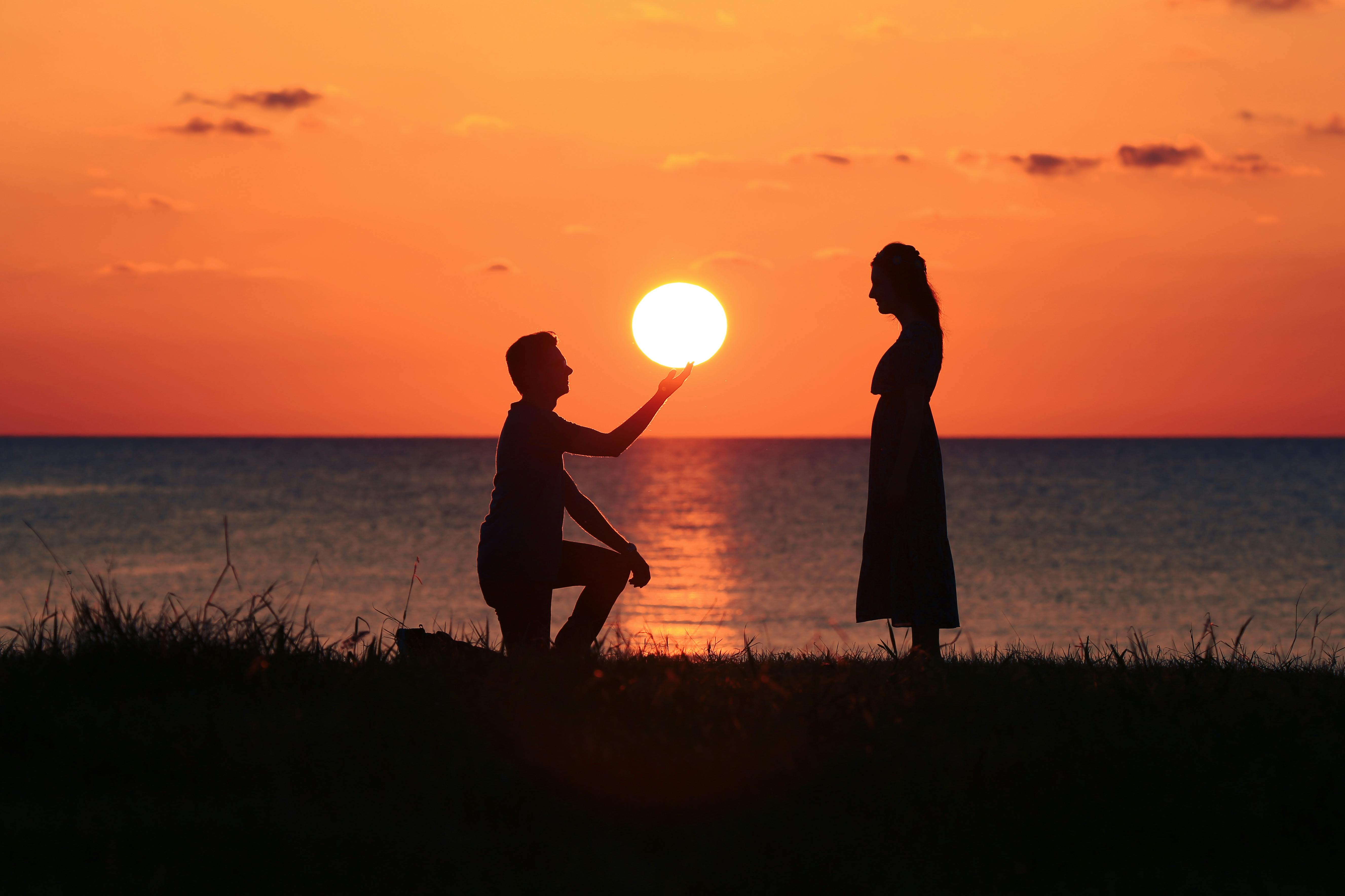 Silueta de hombre arrodillado ante una mujer al atardecer | Fuente: Pexels