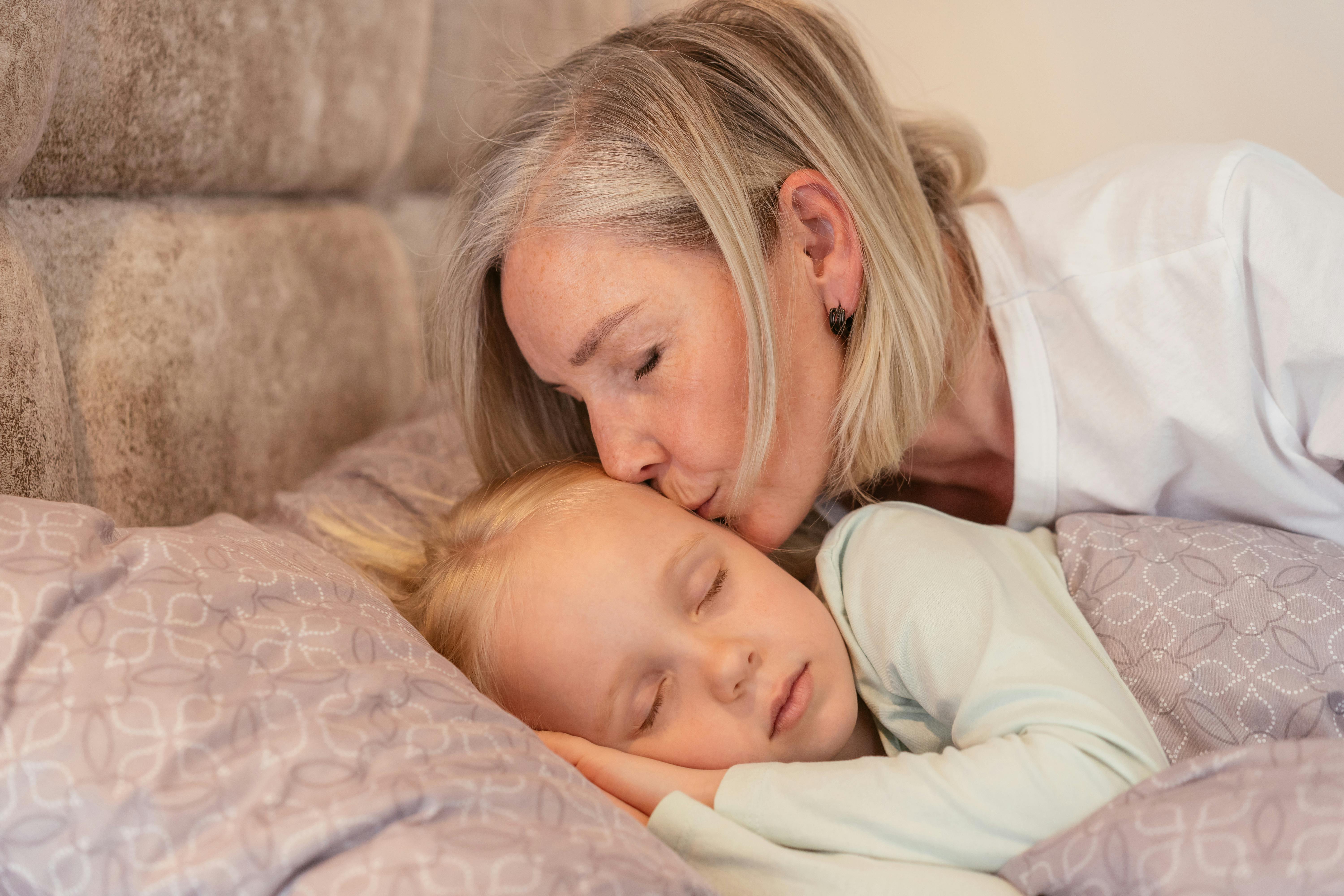 Una abuela arropando a su nieta en la cama | Fuente: Pexels