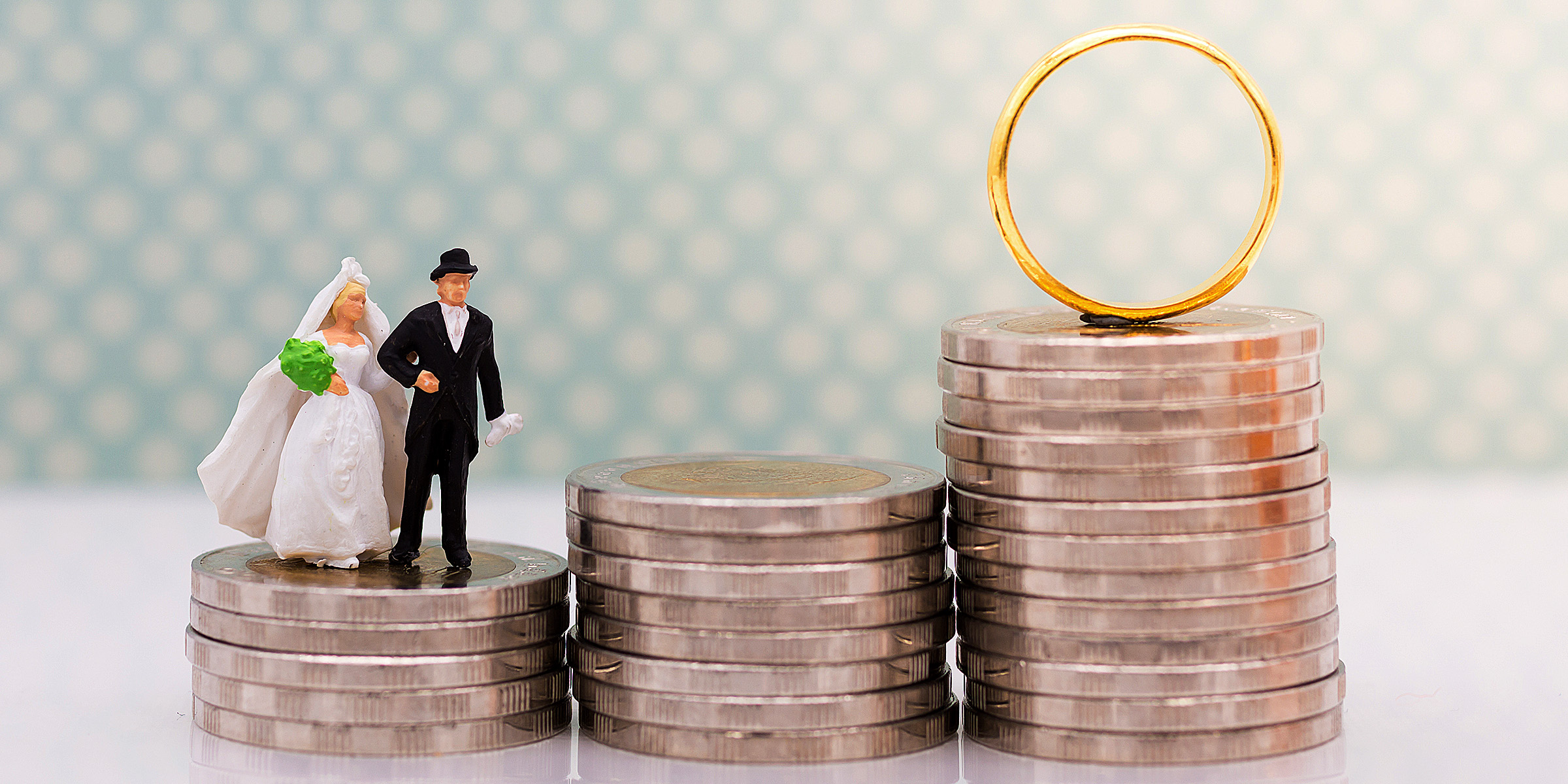 Novios en miniatura de pie sobre una pila de monedas | Fuente: Shutterstock