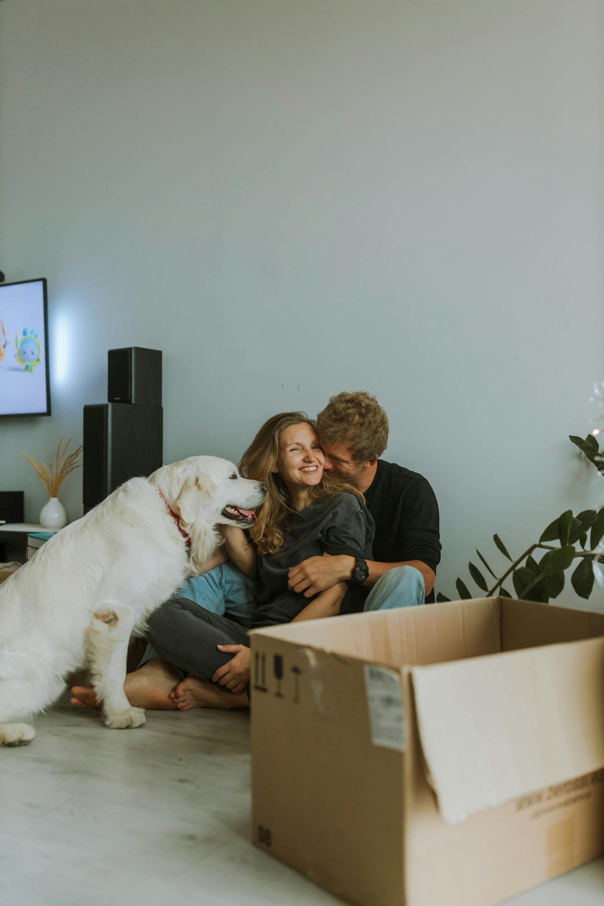 Una pareja feliz abrazada con su perro al lado | Fuente: Pexels