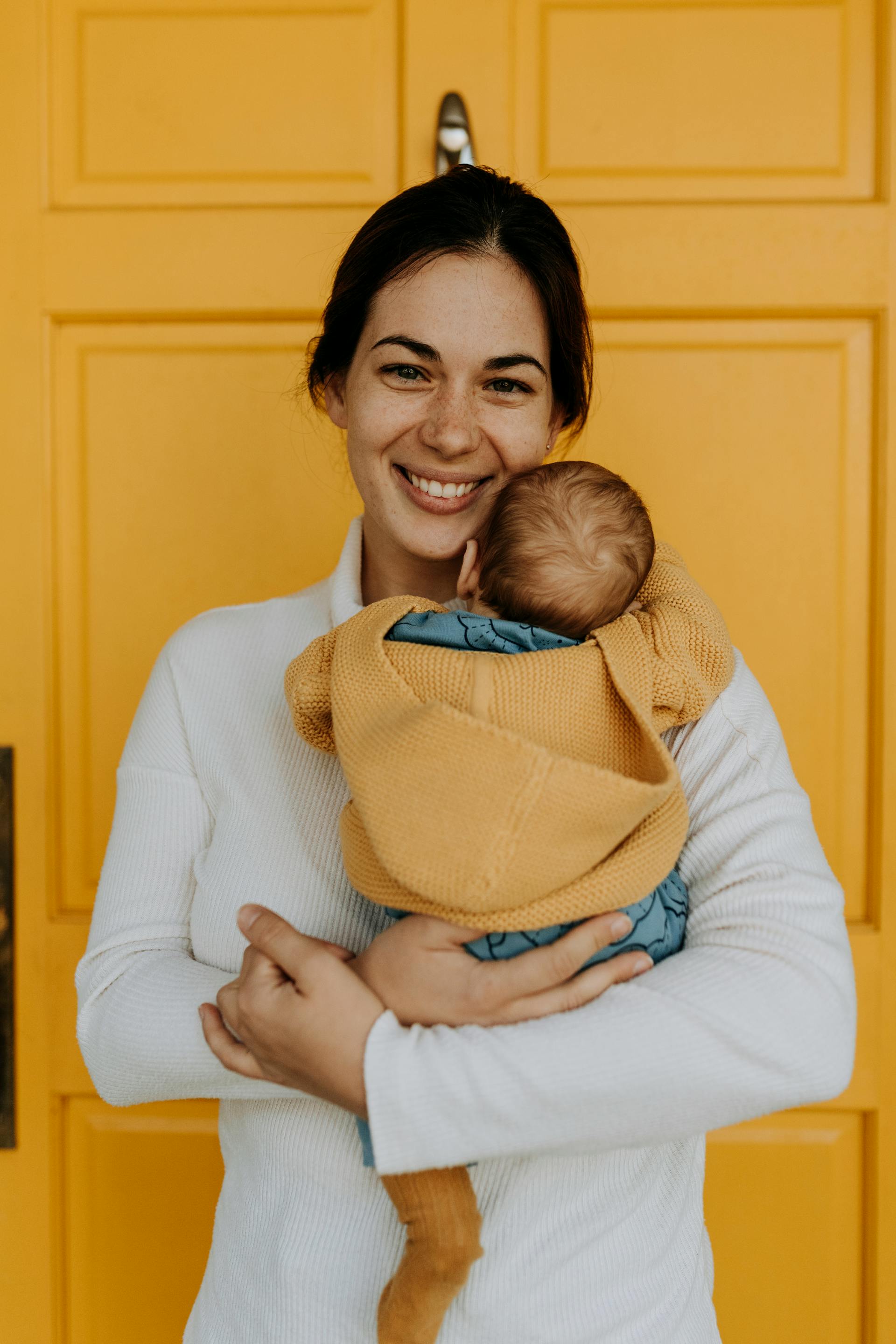 Una mujer feliz con un bebé en brazos | Fuente: Pexels