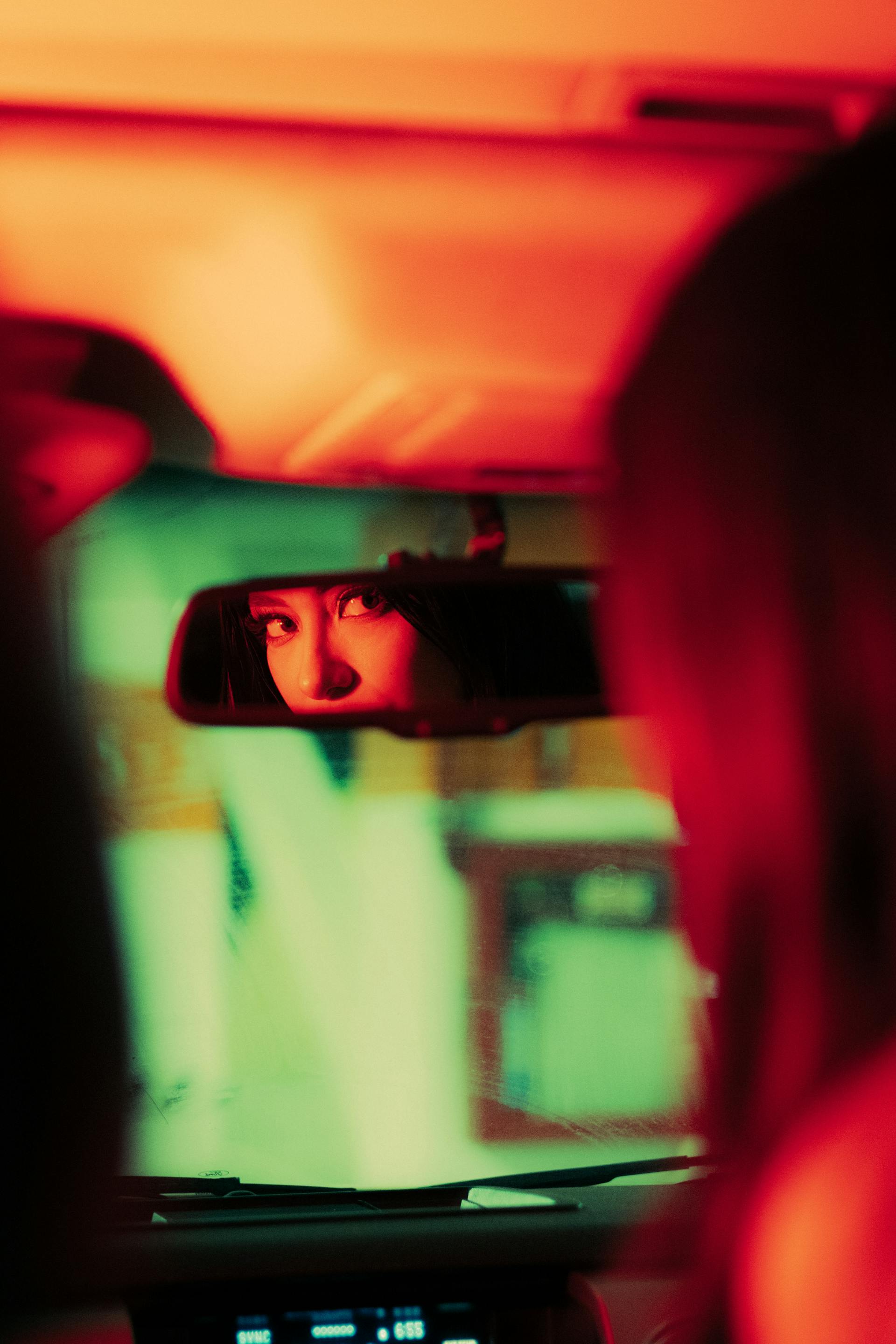 Una mujer usando el espejo retrovisor en un automóvil | Fuente: Pexels