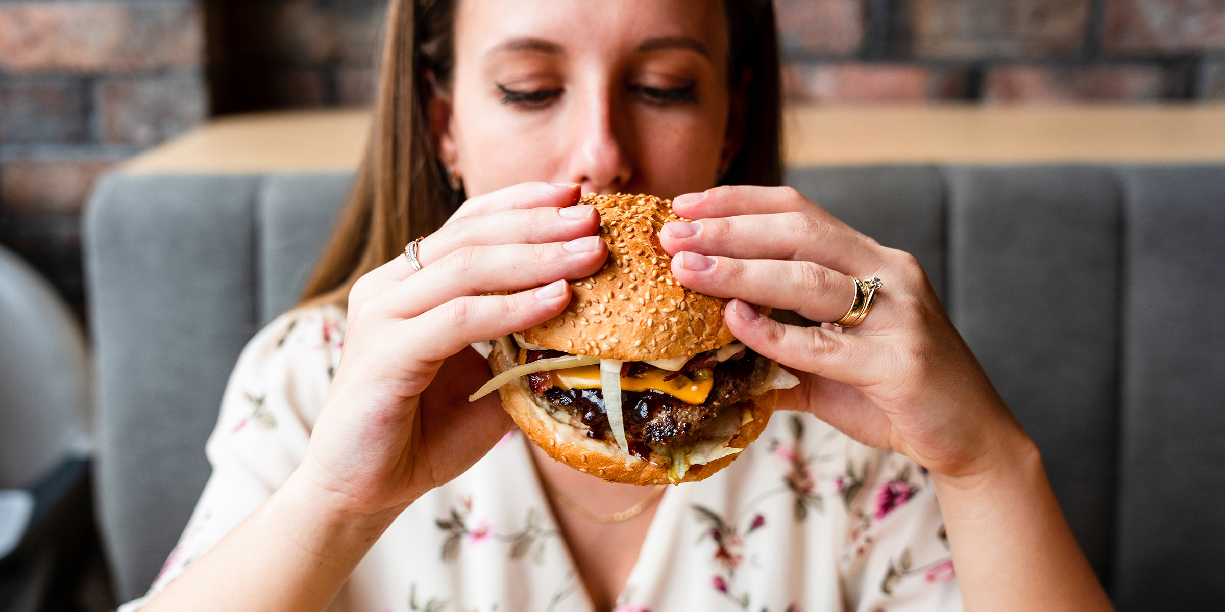 Una mujer comiendo una hamburguesa | Fuente: Shutterstock