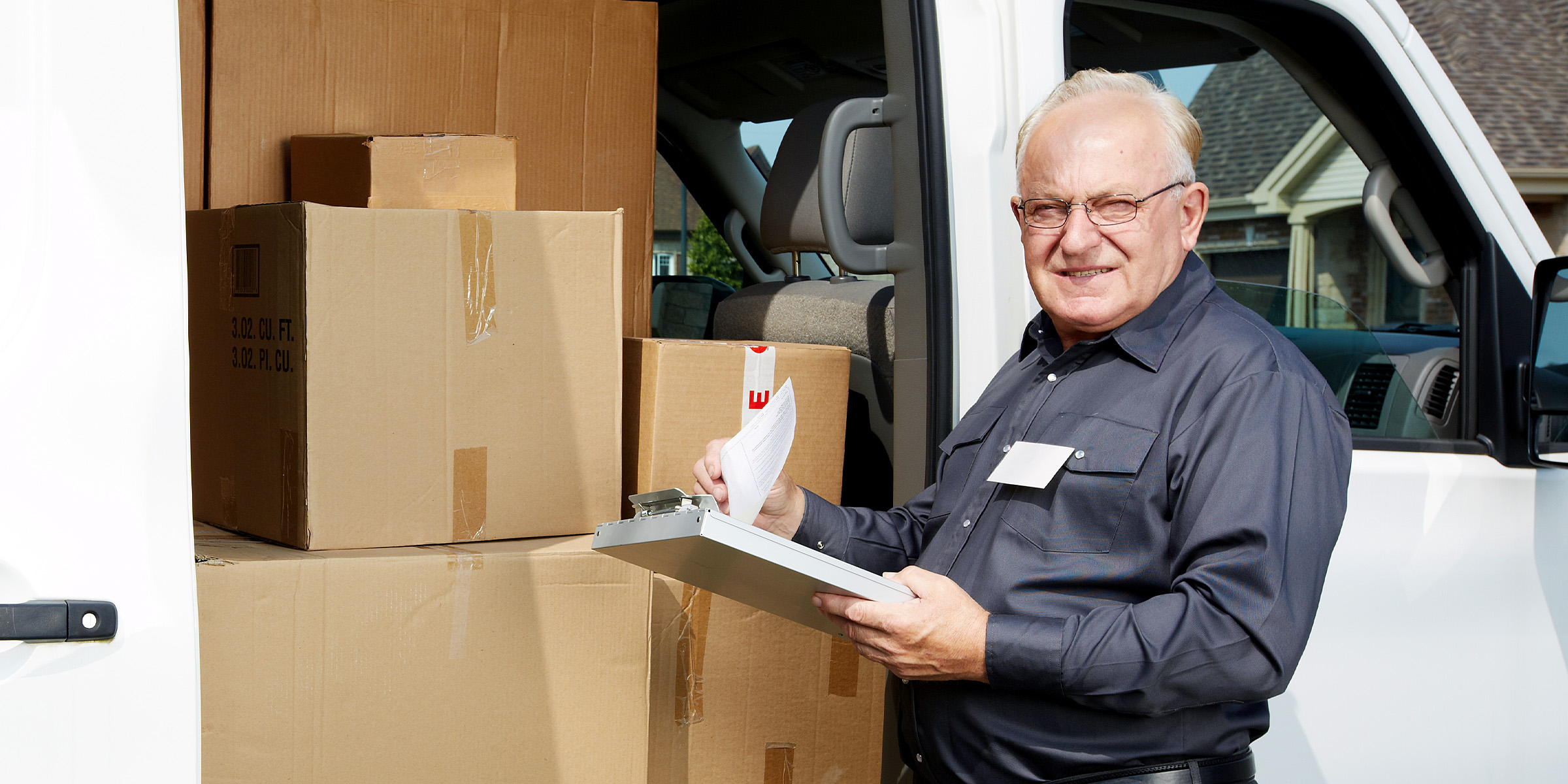 Un cartero de pie junto a un vehículo | Fuente: Shutterstock
