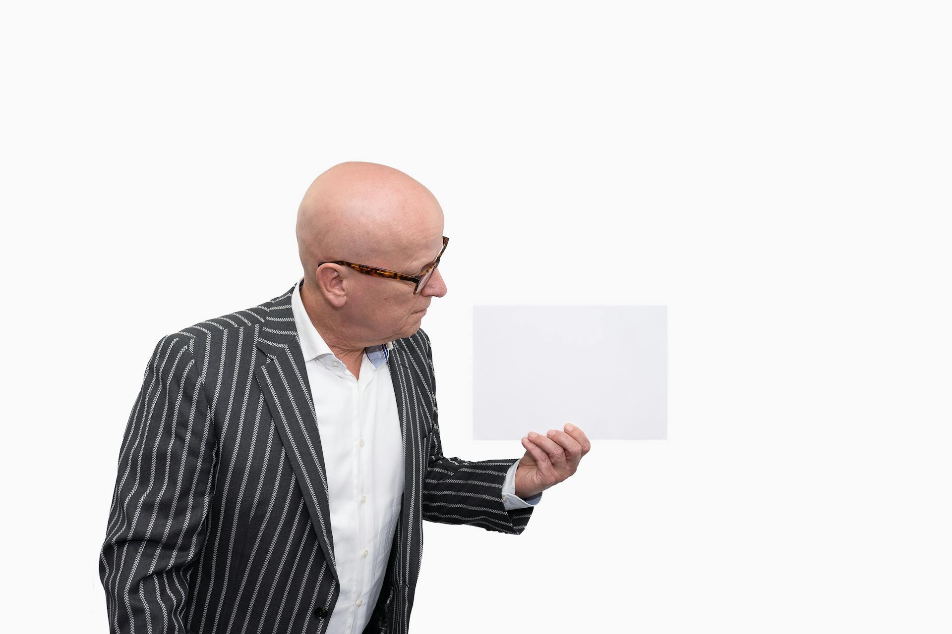 Un hombre mayor sujetando una hoja de papel | Fuente: Pexels