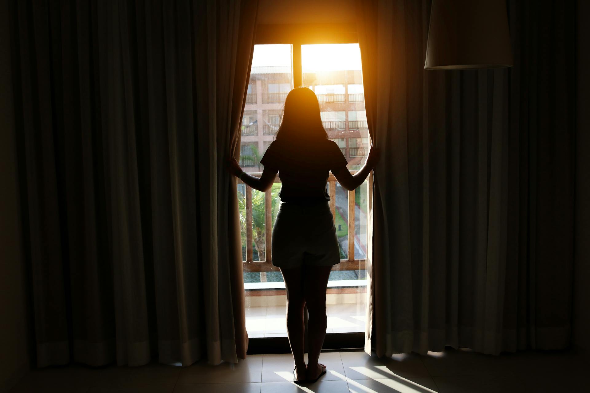 Una joven de pie junto a la ventana | Fuente: Pexels