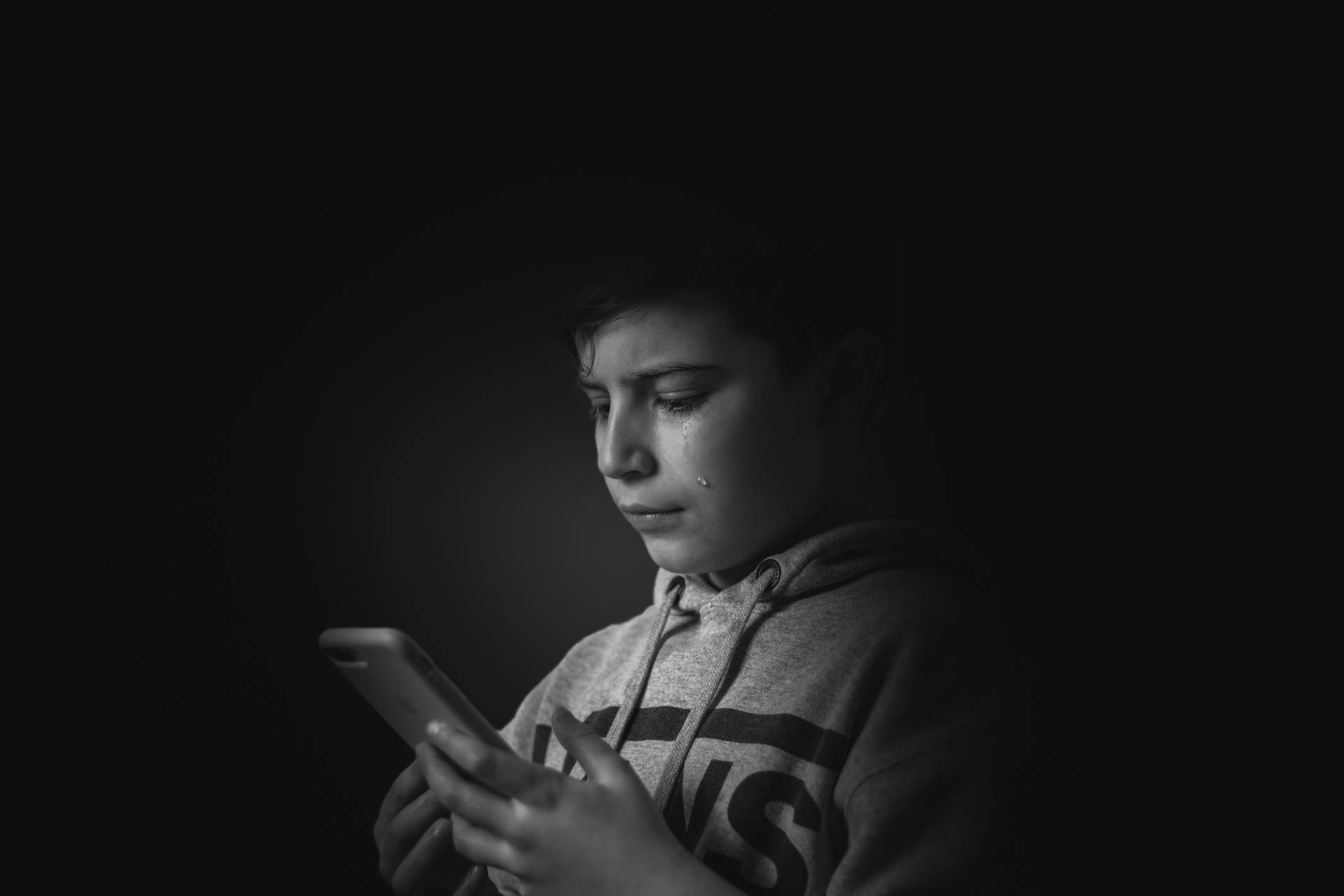 Un niño con los ojos llorosos mirando su teléfono | Fuente: Pexels