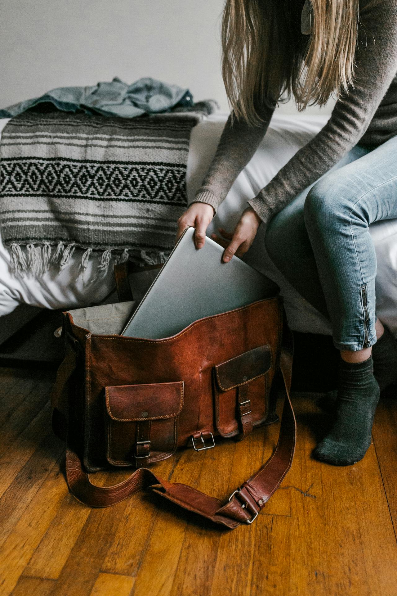 Una mujer metiendo un portátil en una bolsa marrón | Fuente: Pexels