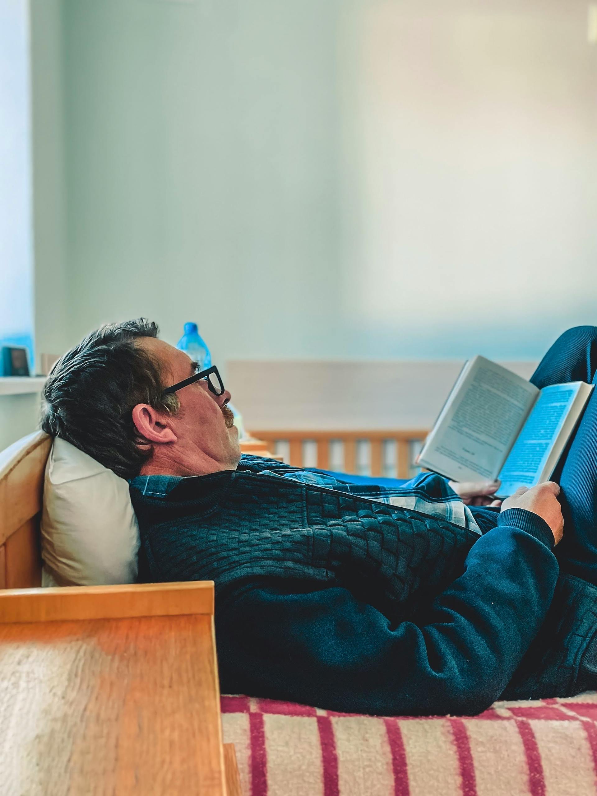 Un hombre tumbado en la cama leyendo | Fuente: Pexels