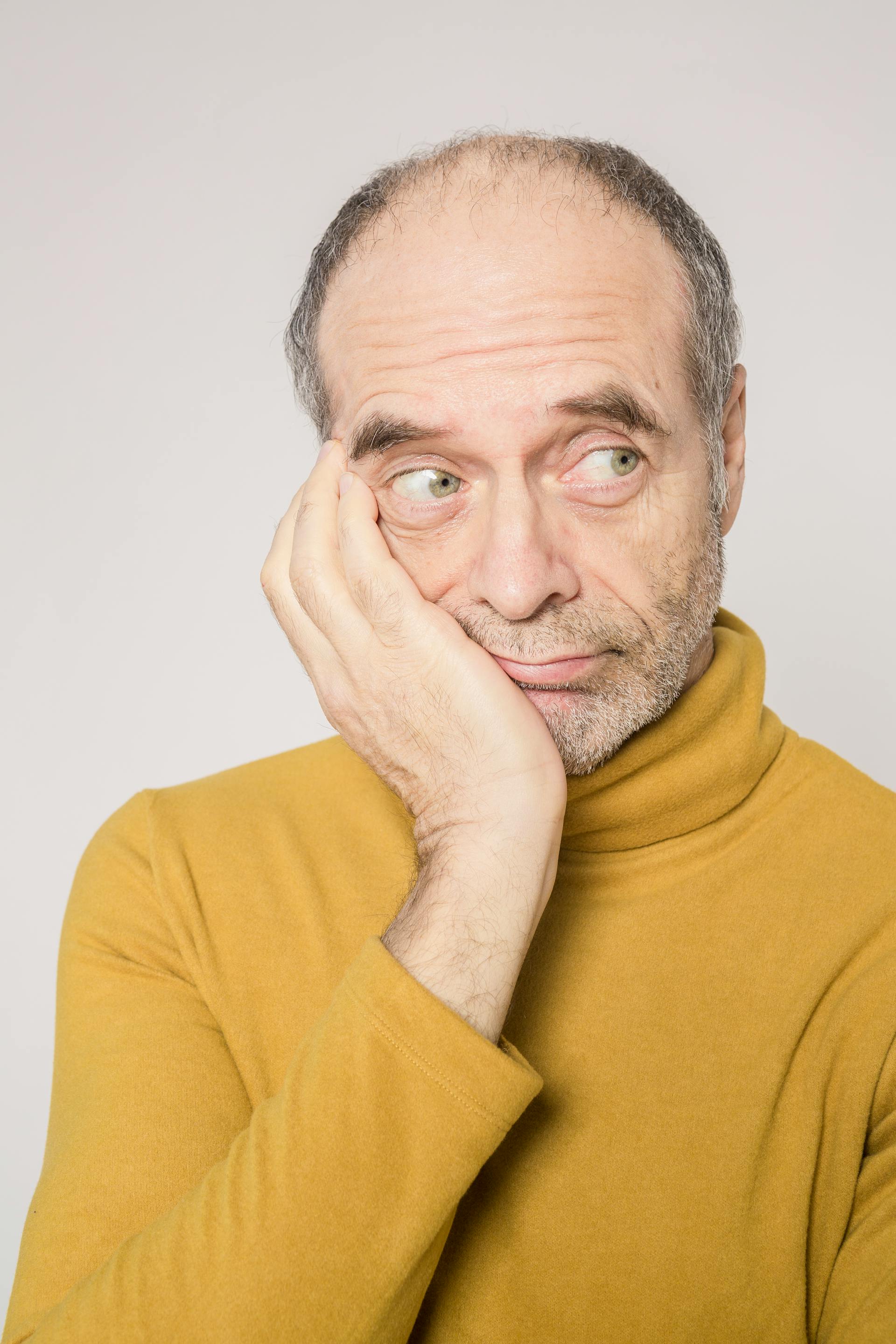 Un hombre mayor con un jersey amarillo mirando de reojo | Fuente: Pexels