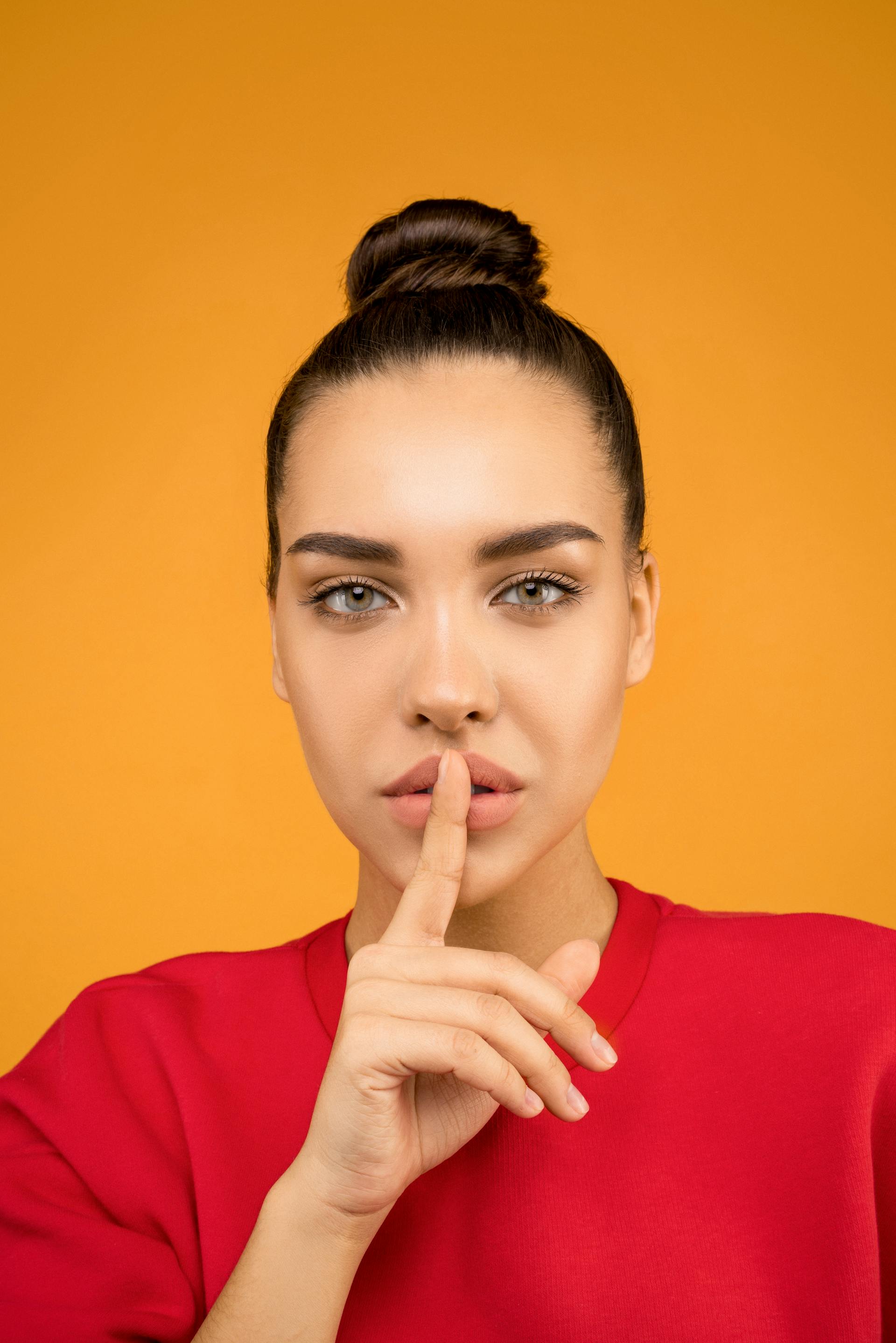 Una mujer llevándose un dedo a los labios | Fuente: Pexels