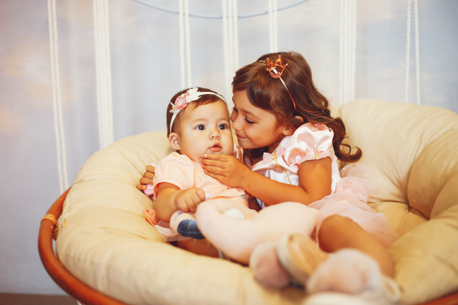 Una niña y una bebé sentadas en una silla | Fuente: Freepik