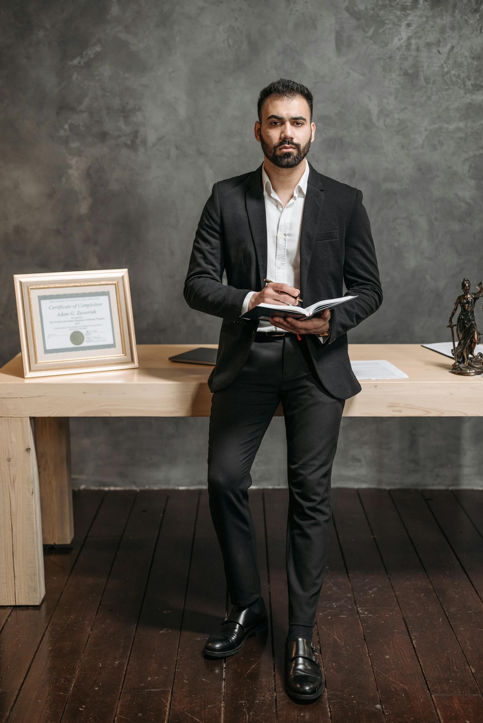 Hombre con traje negro sujetando un cuaderno | Fuente: Pexels
