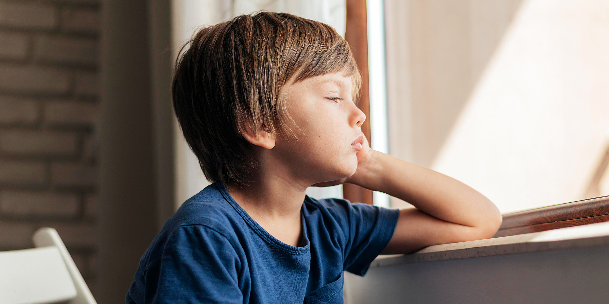 Un niño triste sentado junto a la ventana | Fuente: Freepik