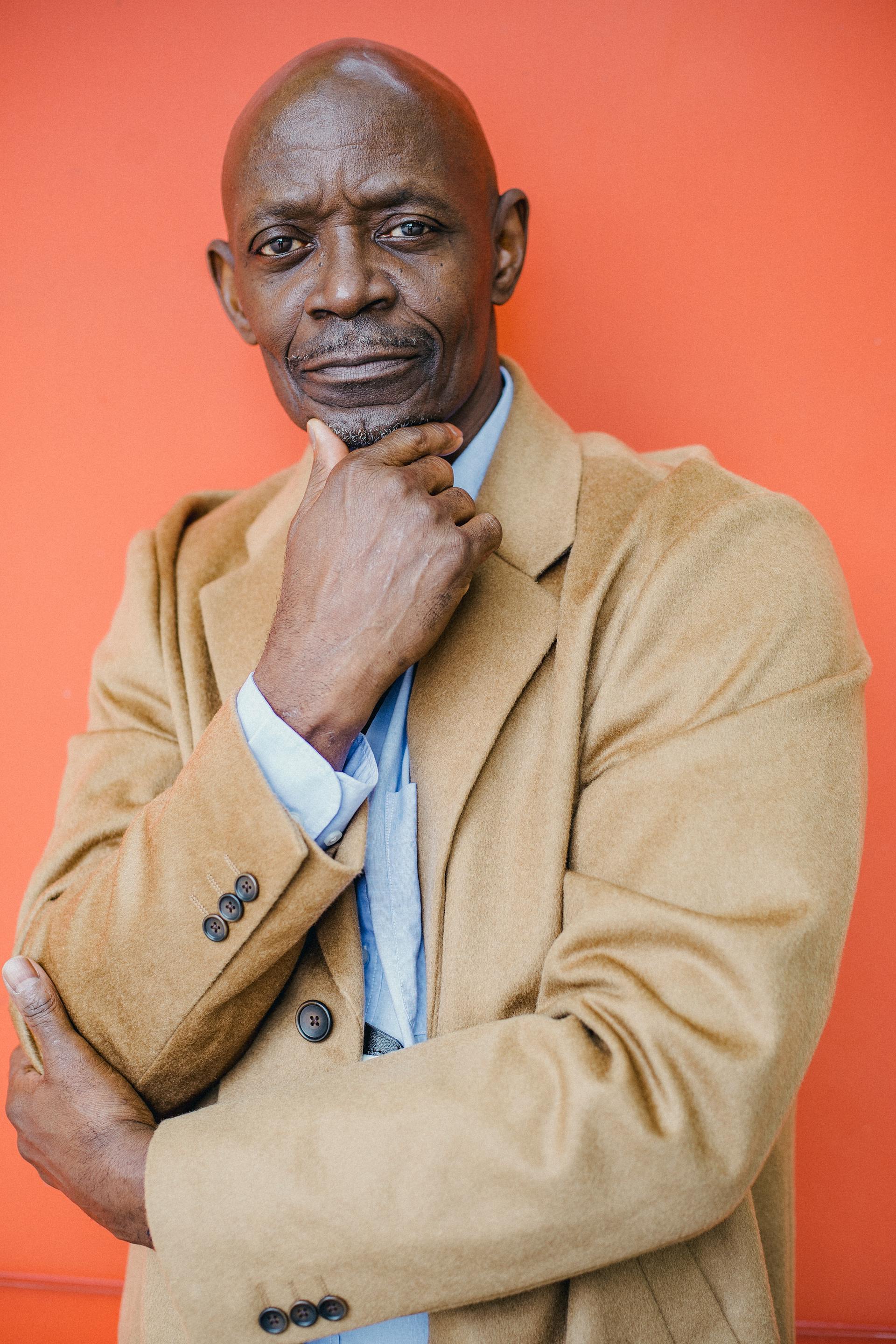 Un hombre negro con abrigo mirando a alguien | Fuente: Pexels