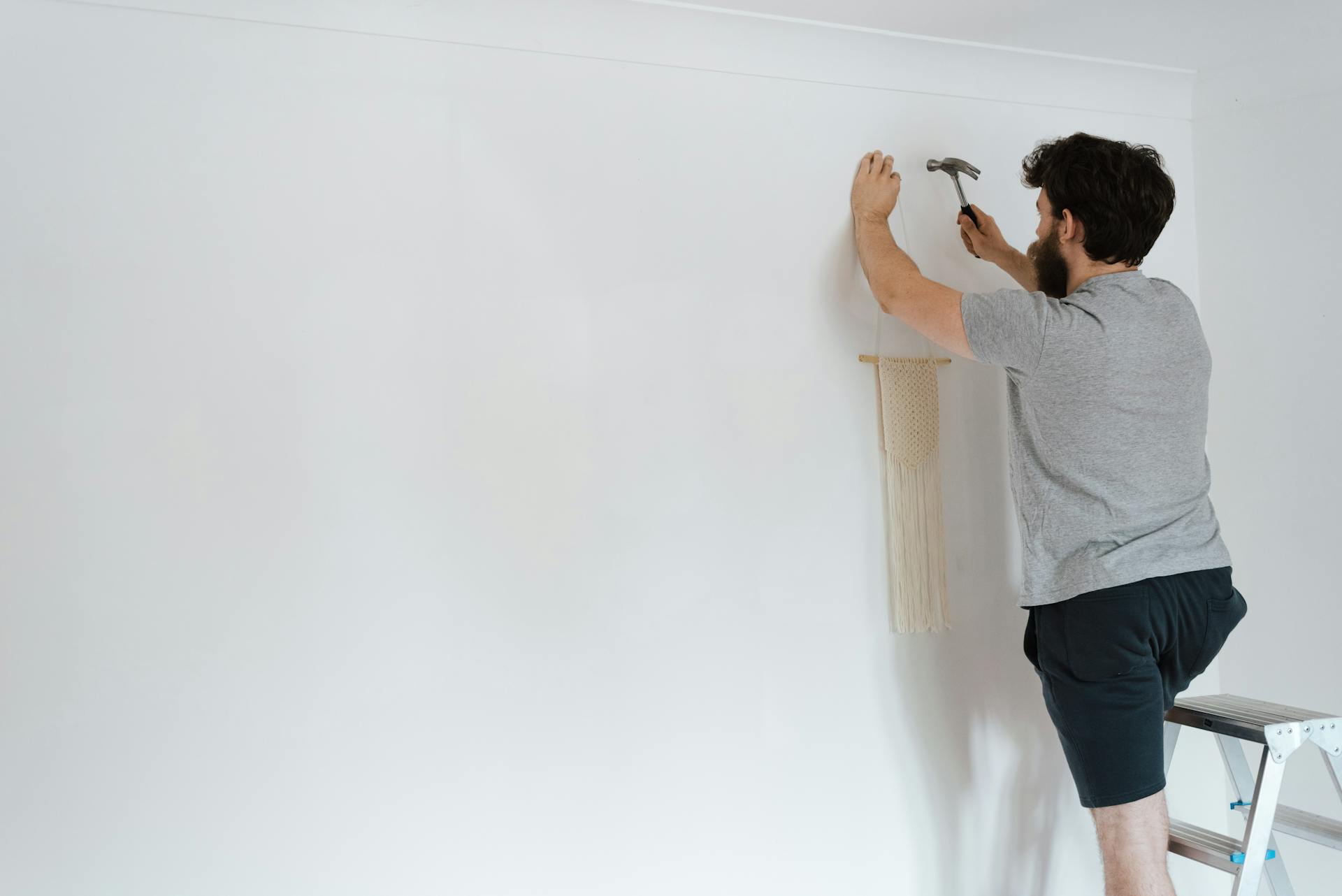 Un hombre colocando una pieza de decoración en una pared | Fuente: Pexels