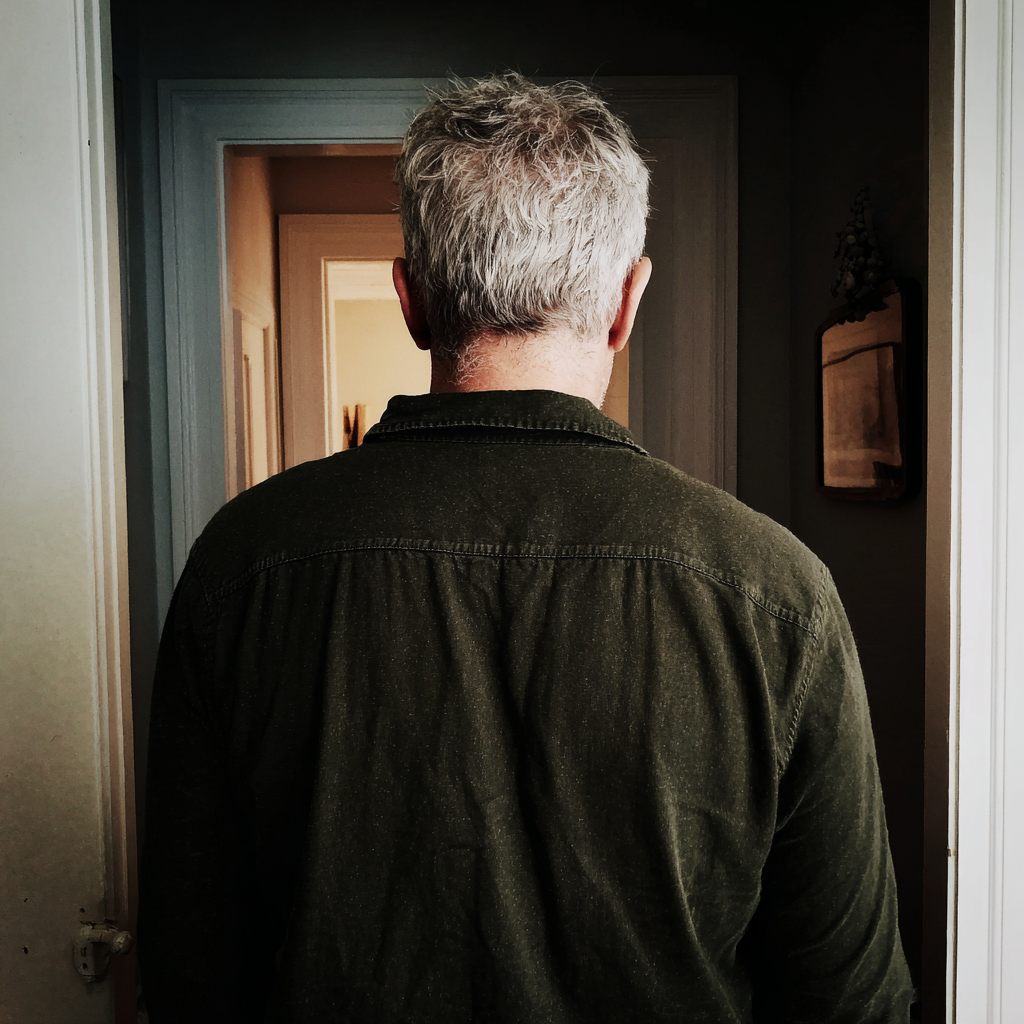 Vista trasera de un hombre mayor en el pasillo de una casa | Fuente: Midjourney