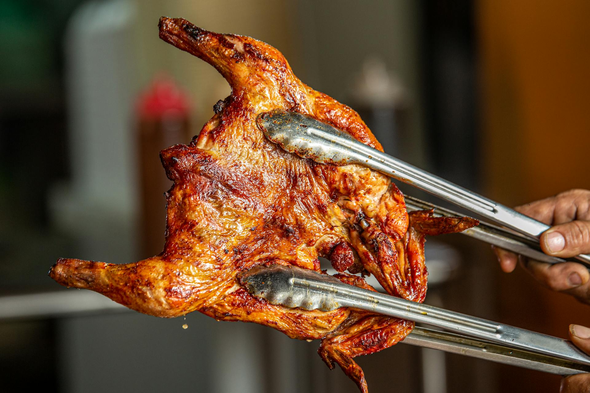 Una persona sujetando un pollo asado | Fuente: Pexels