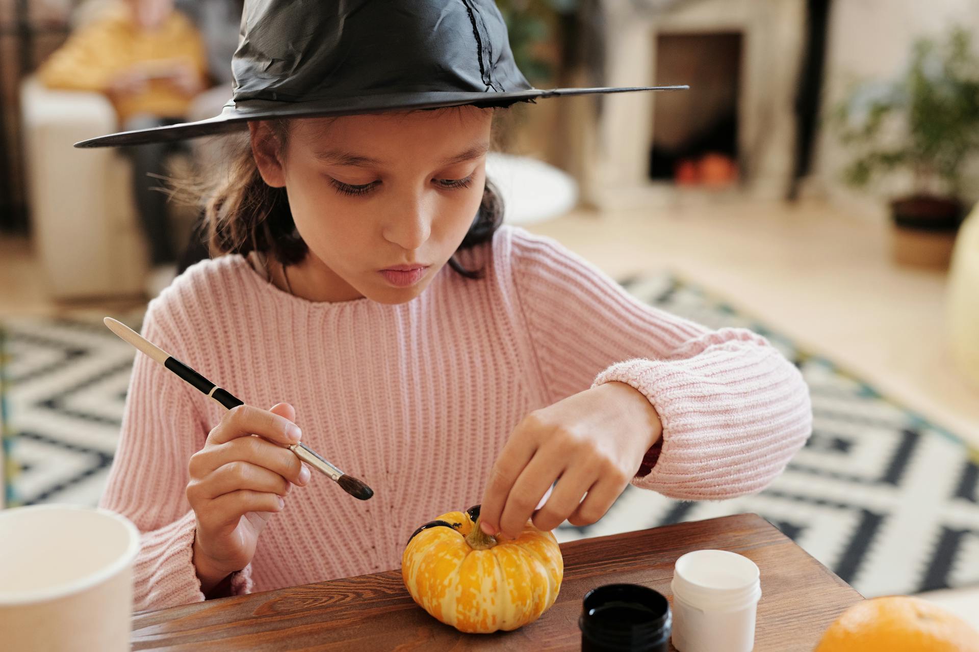 Una chica pintando una calabaza | Fuente: Pexels