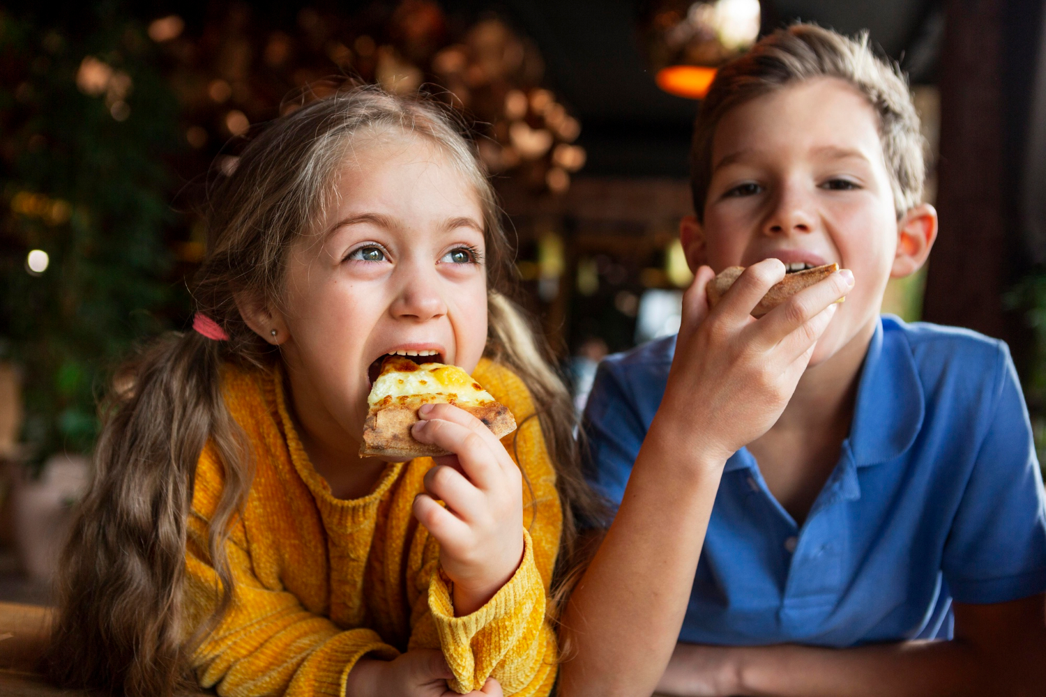 Niños emocionados comiendo pizza | Fuente: Freepik