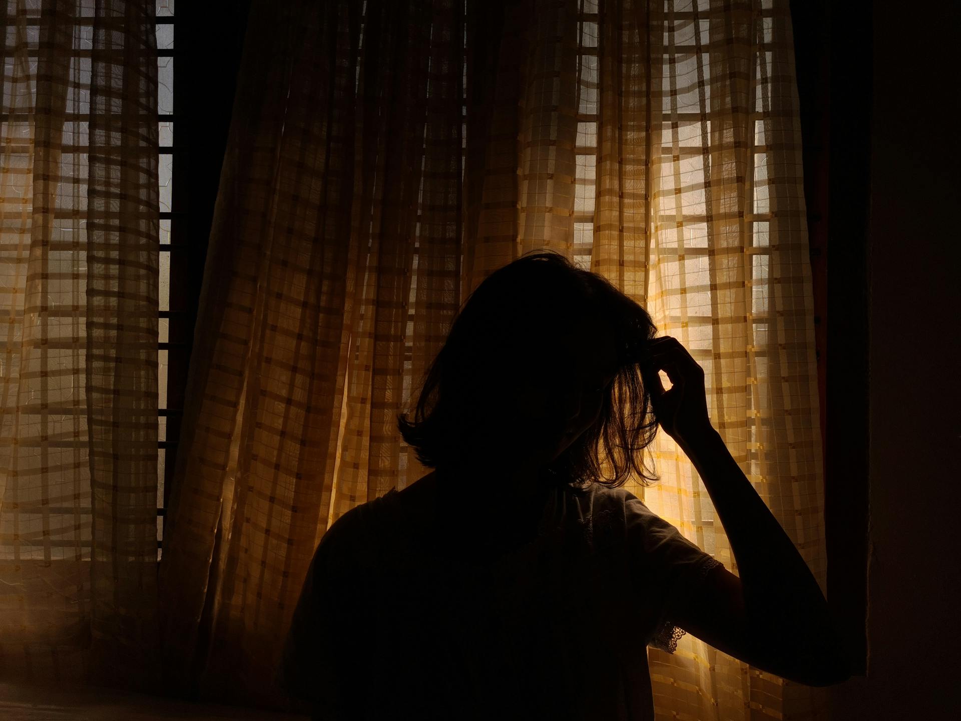 Una mujer junto a las cortinas | Fuente: Pexels