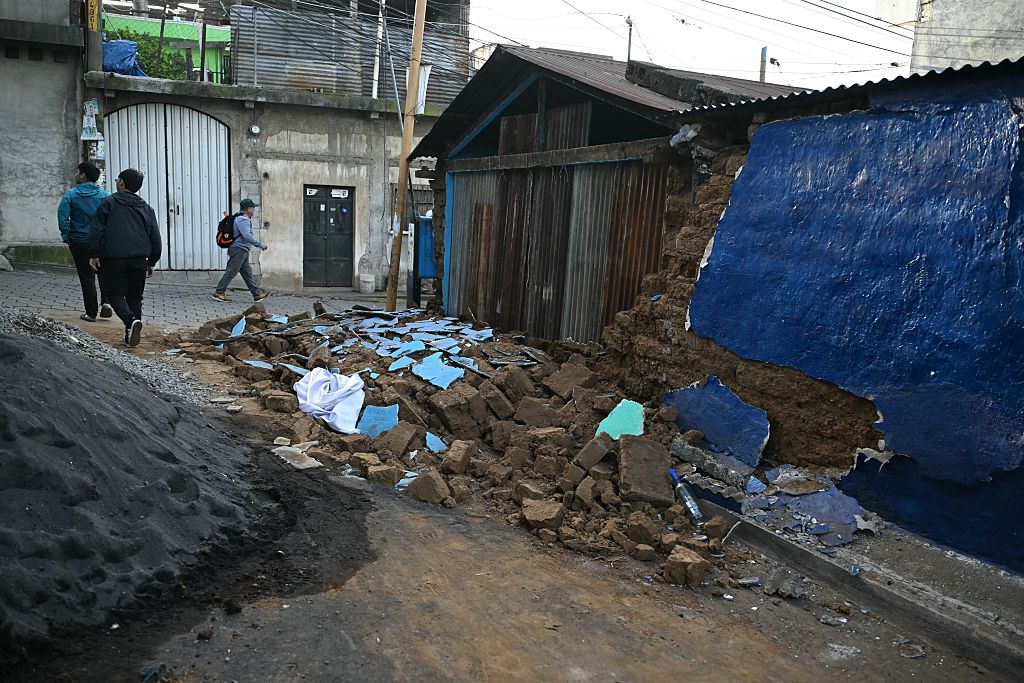 Personas pasan junto al muro derrumbado de una casa tras una serie de sismos que sacudieron la zona en Palin, Guatemala, el 9 de julio de 2025. | Foto: Getty Images