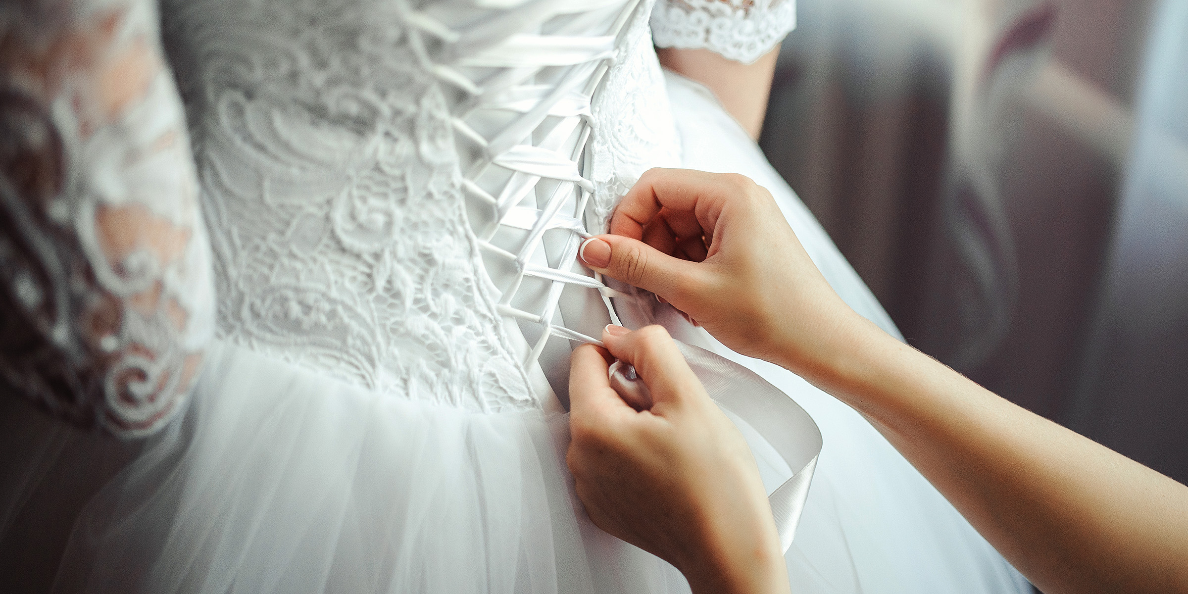 Una mujer ata el corpiño de un vestido de novia | Fuente: Freepik