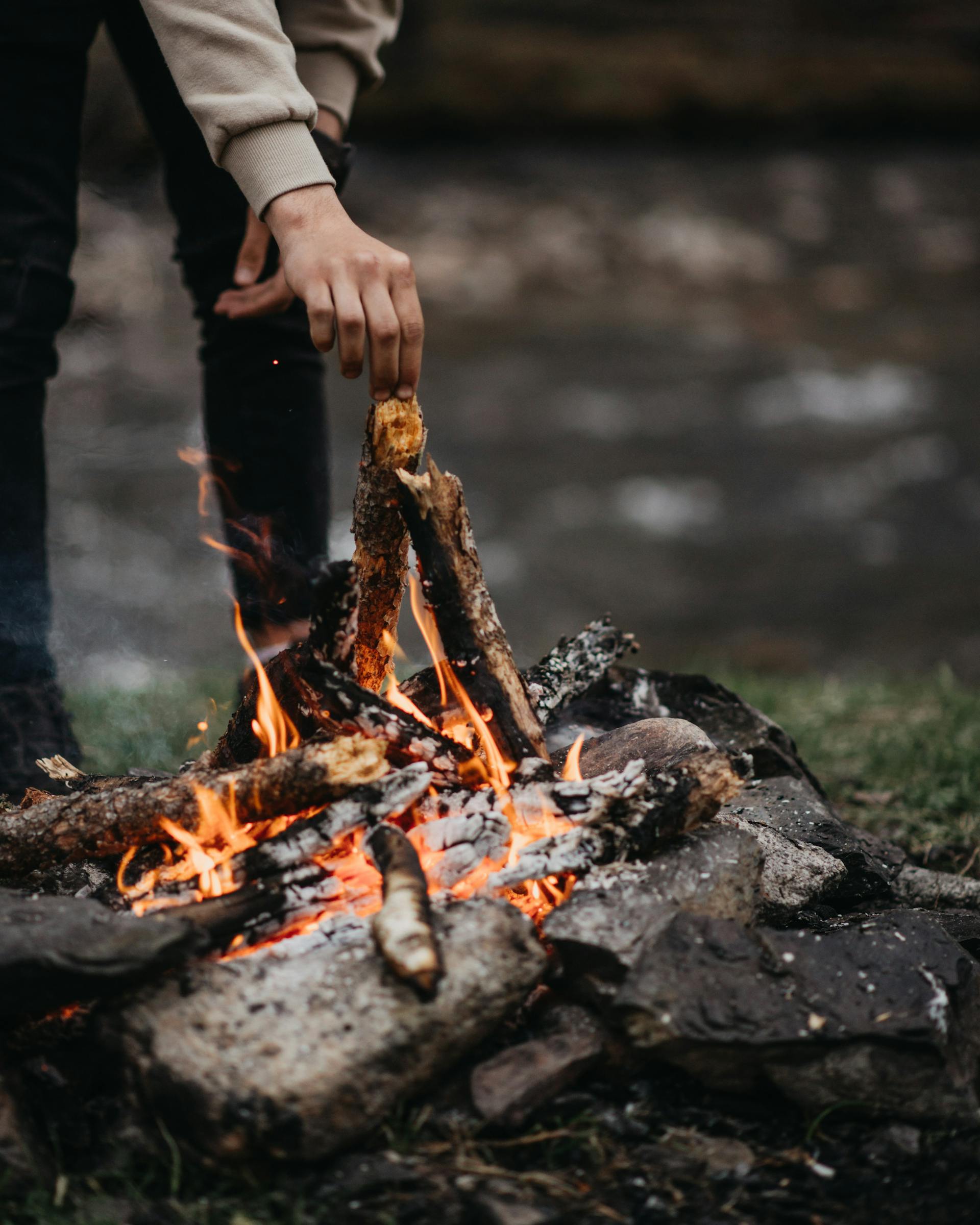Un hombre echando leña al fuego | Fuente: Pexels