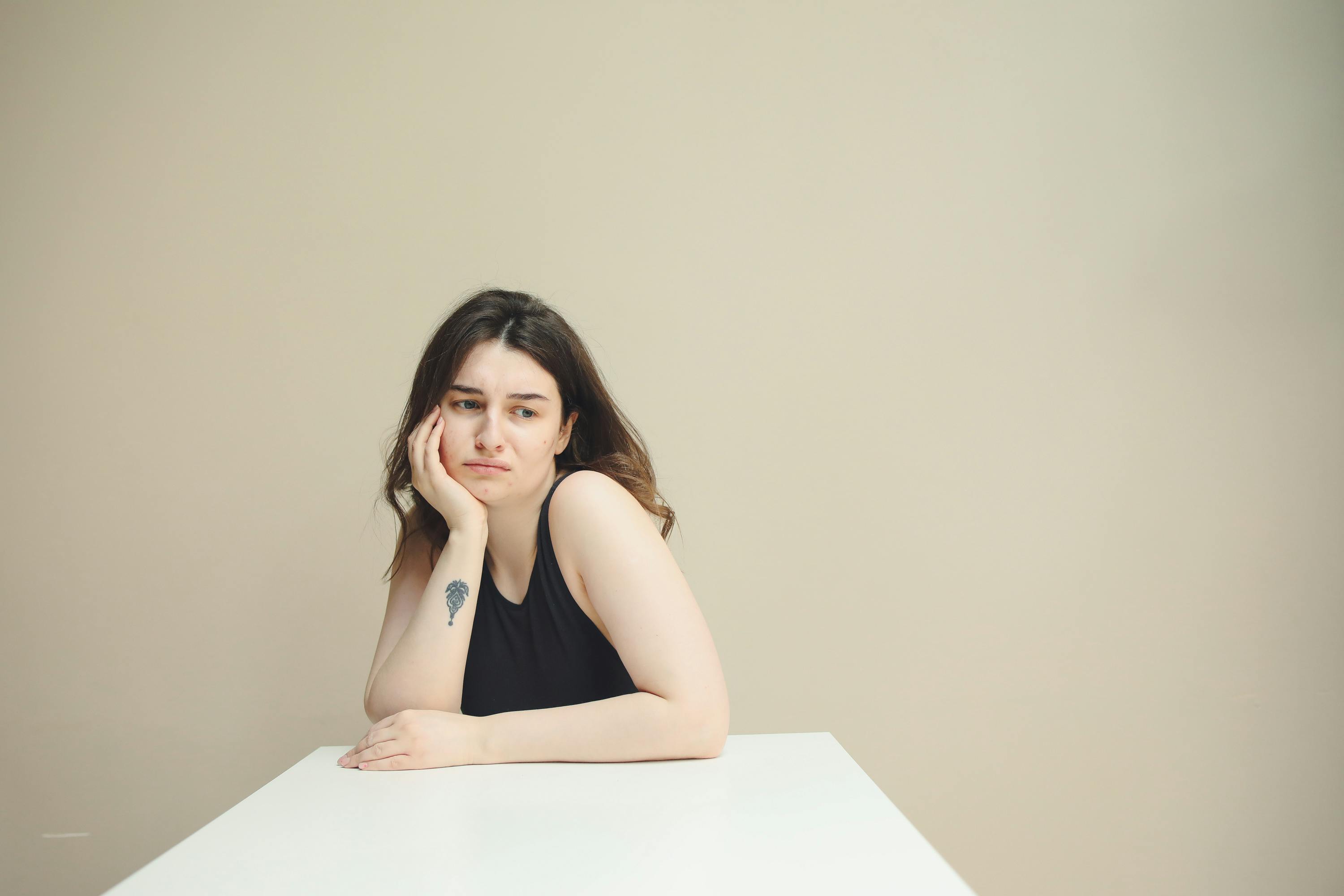 Una mujer pensativa sentada a una mesa | Fuente: Pexels