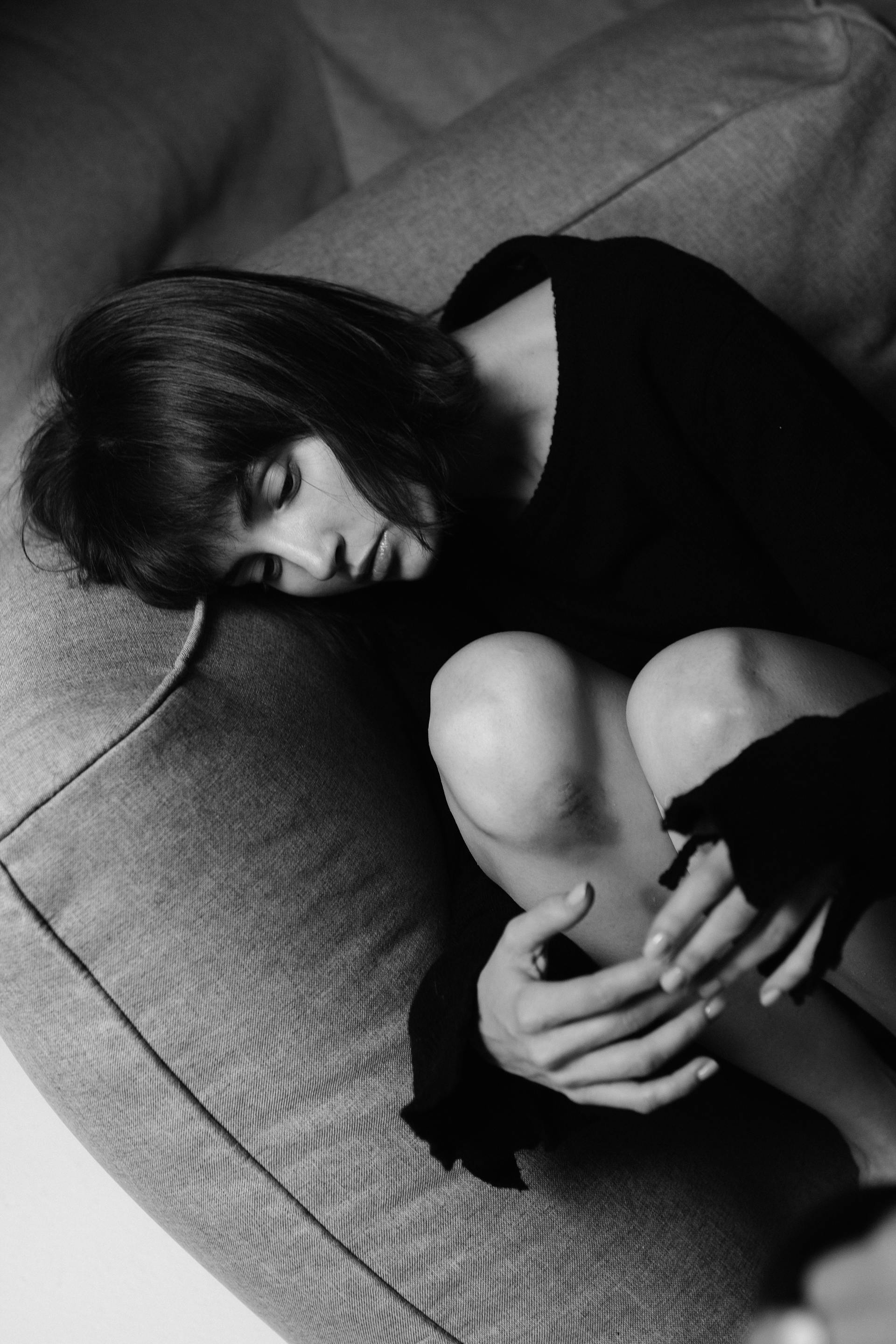 Foto en escala de grises de una mujer tumbada en el sofá | Fuente: Pexels