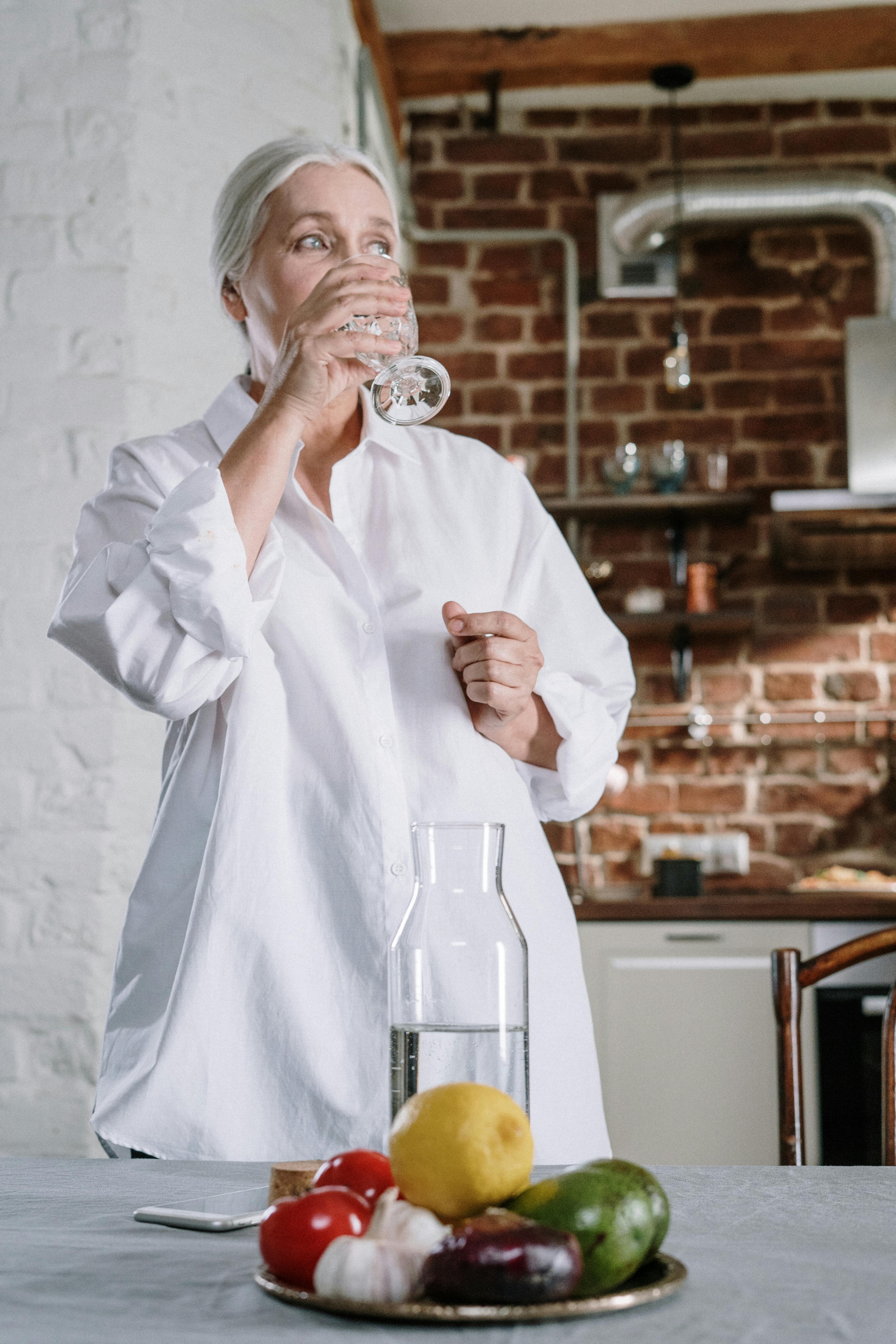 Una mujer mayor bebiendo un vaso de agua | Fuente: Pexels