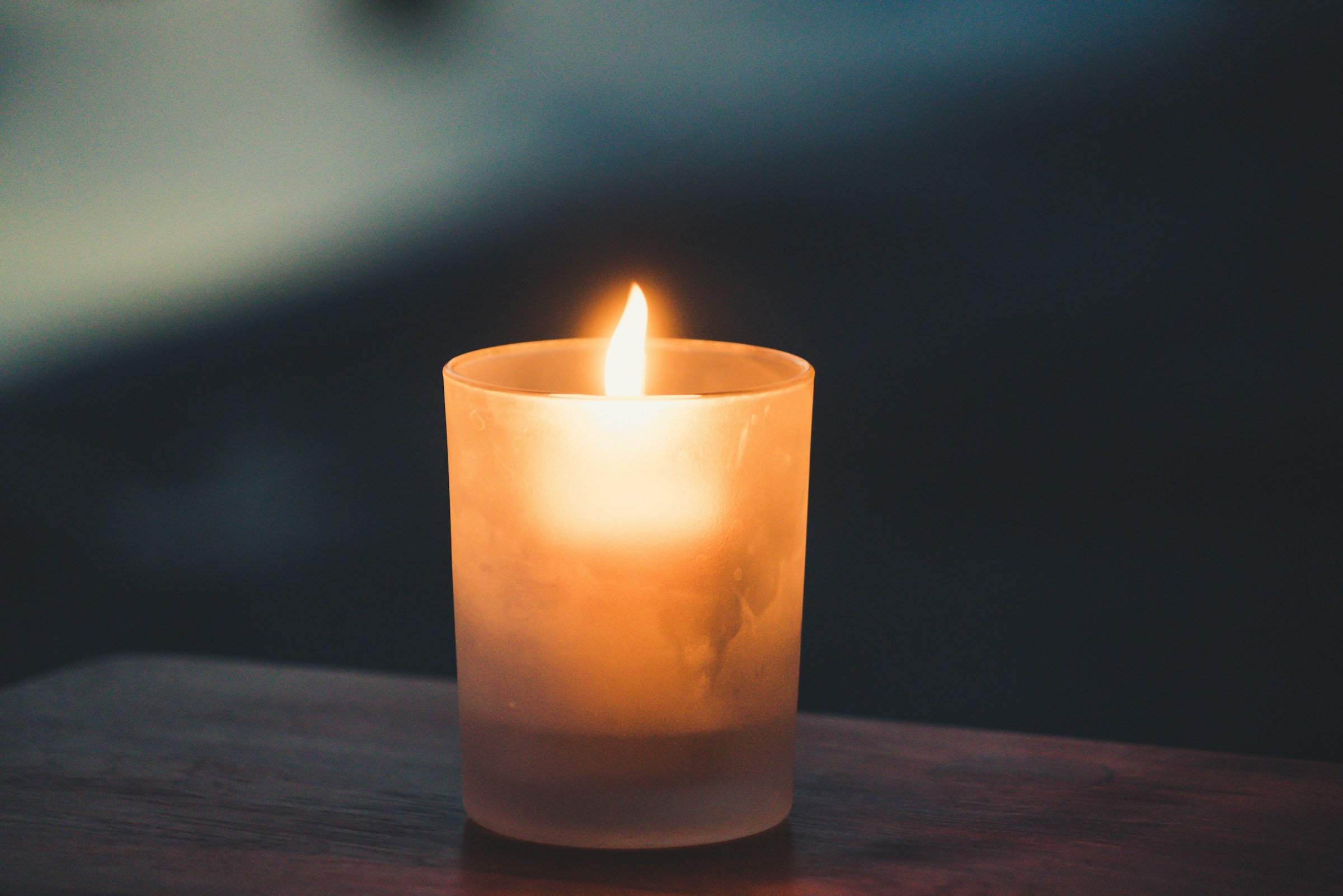 Una vela encendida sobre una superficie de madera | Fuente: Unsplash