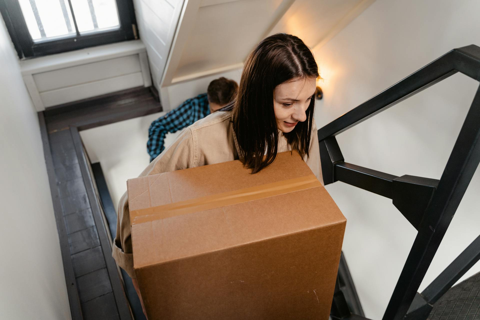 Una mujer lleva una caja mientras sube las escaleras de su casa | Fuente: Pexels