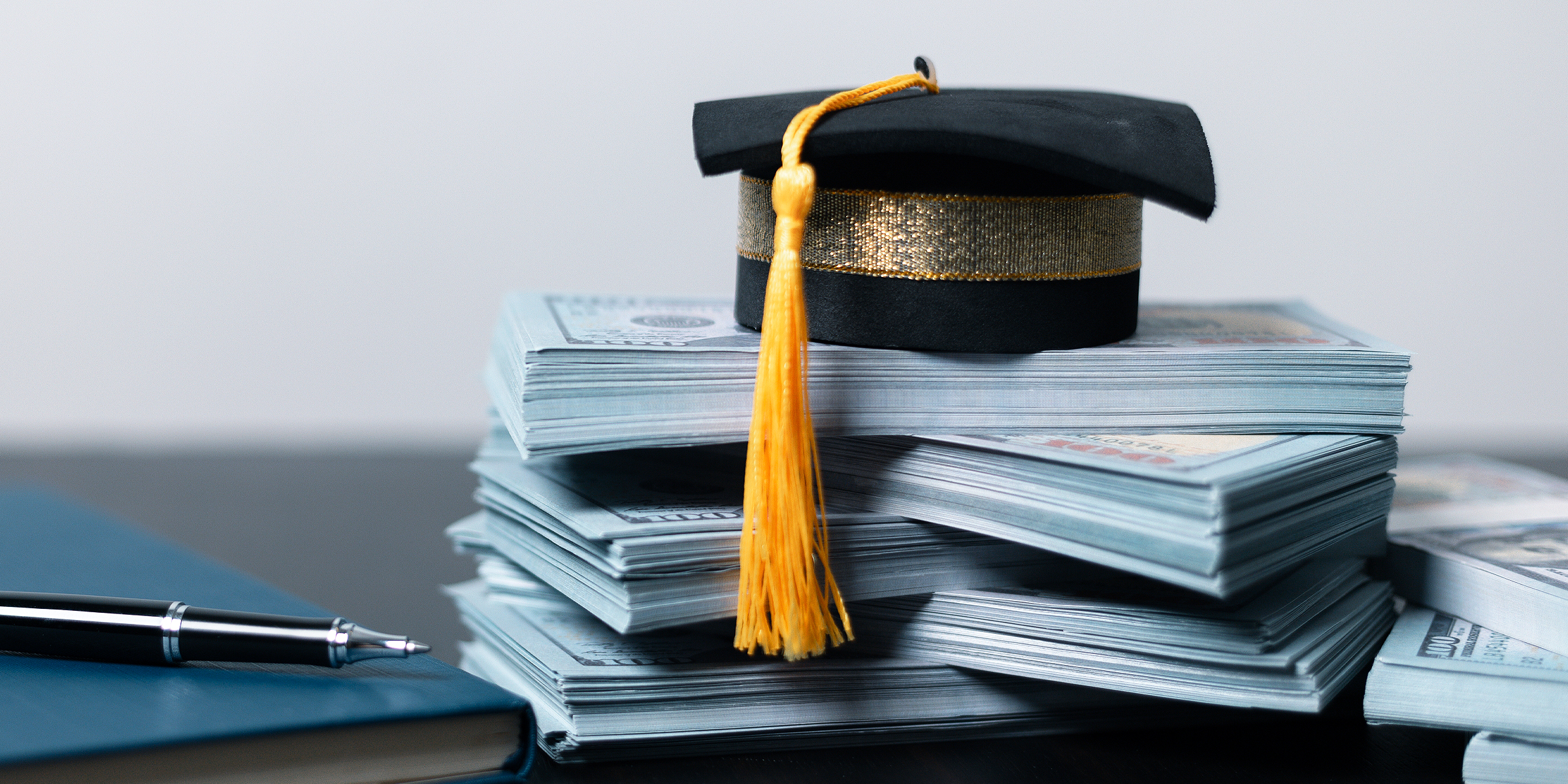 Un birrete de graduación colocado sobre montones de dinero | Fuente: Shutterstock