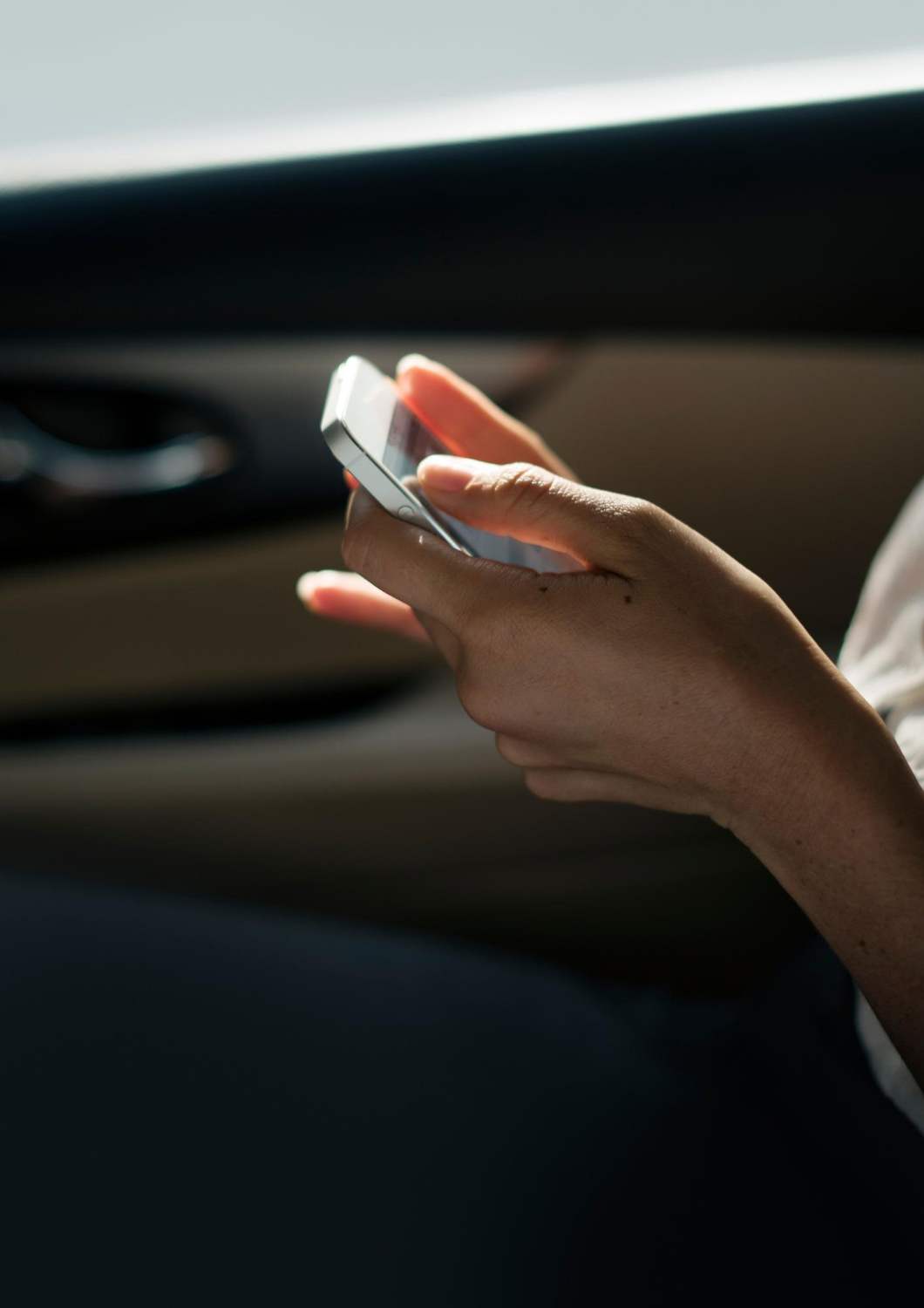 Una mujer sostiene su teléfono mientras está sentada en un automóvil | Fuente: Freepik