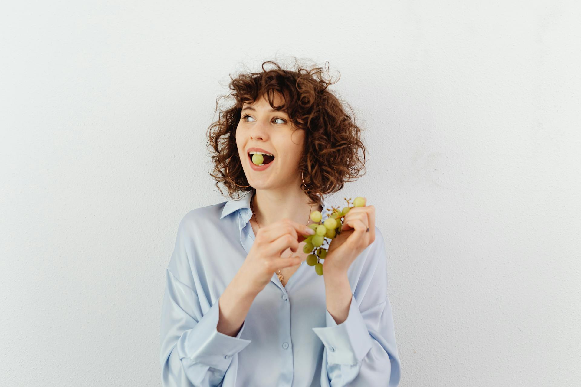 Una mujer de pelo rizado comiendo uvas | Fuente: Pexels