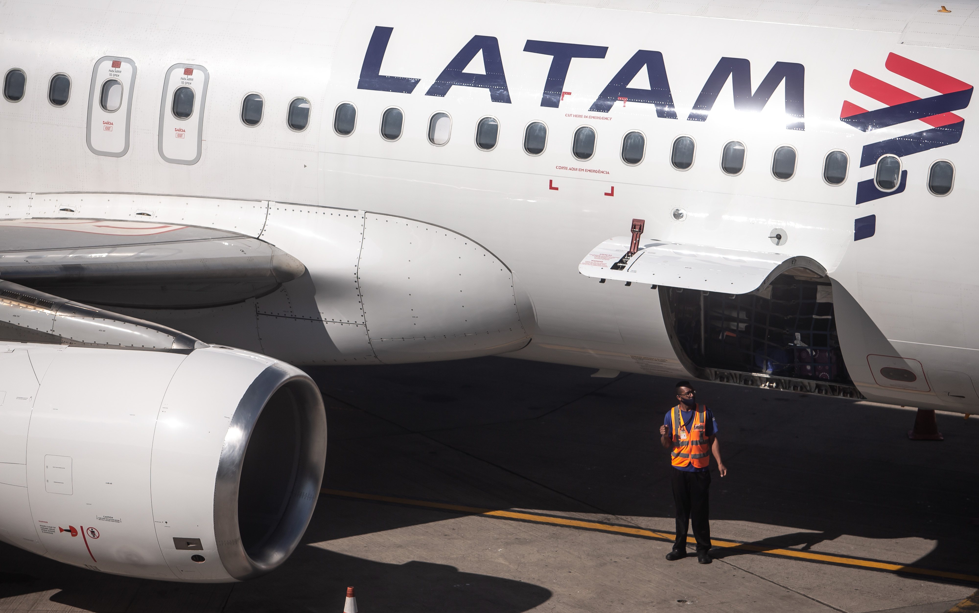 Un trabajador se encuentra frente a la bodega de equipaje de un avión operado por Latam Airlines Group SA en el Aeropuerto Internacional de Guarulhos (GRU) en São Paulo, Brasil, el viernes 10 de julio de 2020. | Fuente: Getty Images