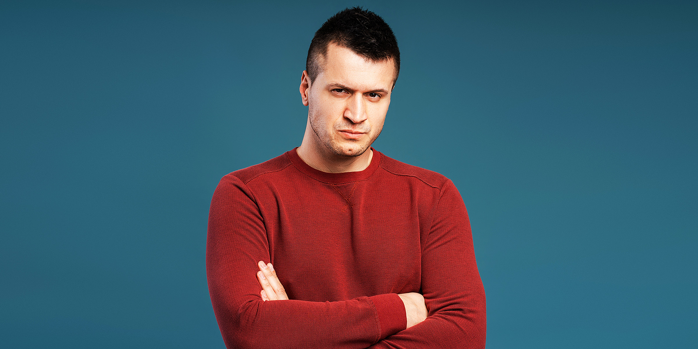 Un hombre de pie con los brazos cruzados | Fuente: Shutterstock