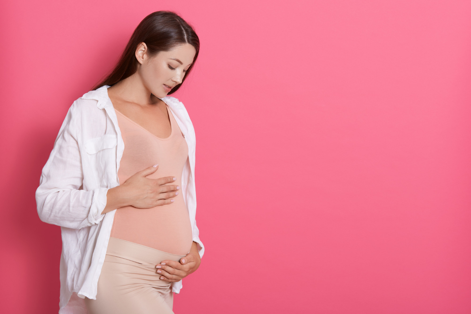 Una mujer embarazada mirando su barriguita | Fuente: Freepik