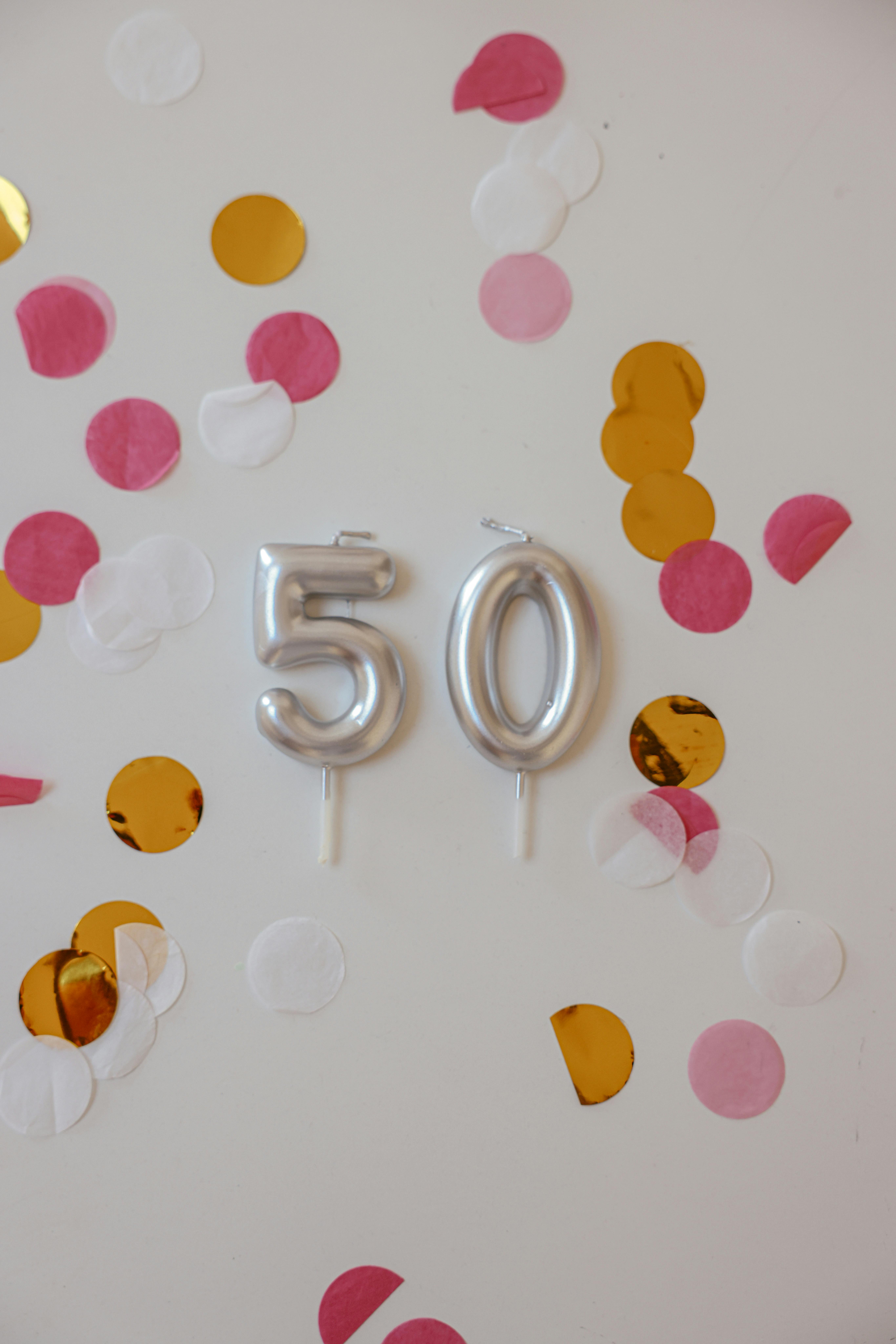 Globos plateados y confeti de colores en una pared | Fuente: Pexels
