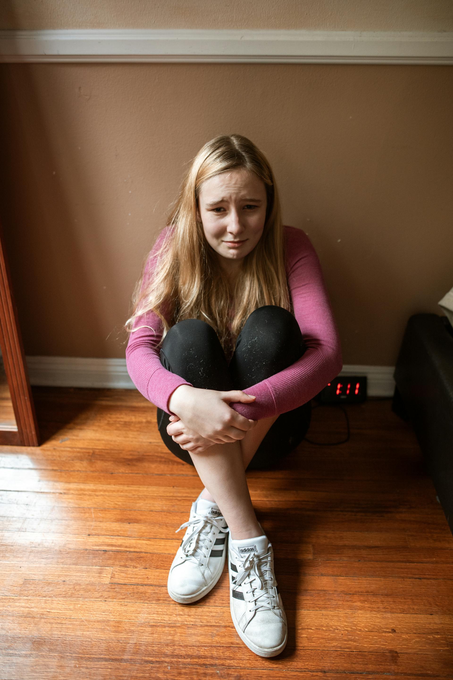 Una adolescente sentada en el suelo y llorando | Fuente: Pexels