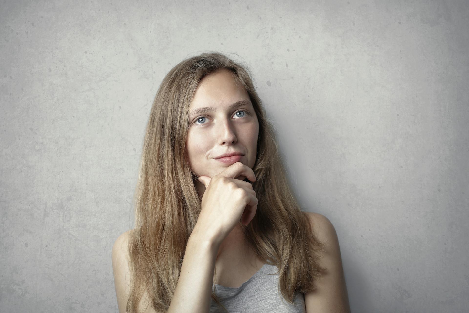 Una mujer sonriendo pensativa | Fuente: Pexels