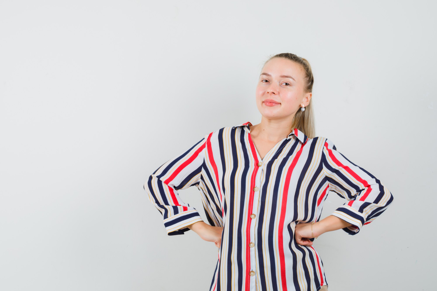 Una mujer sonriente con las manos en las caderas | Fuente: Freepik